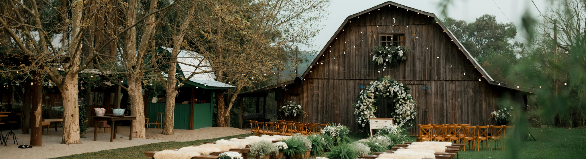 A rustic barn wedding venue in a rural area surrounded by green trees.