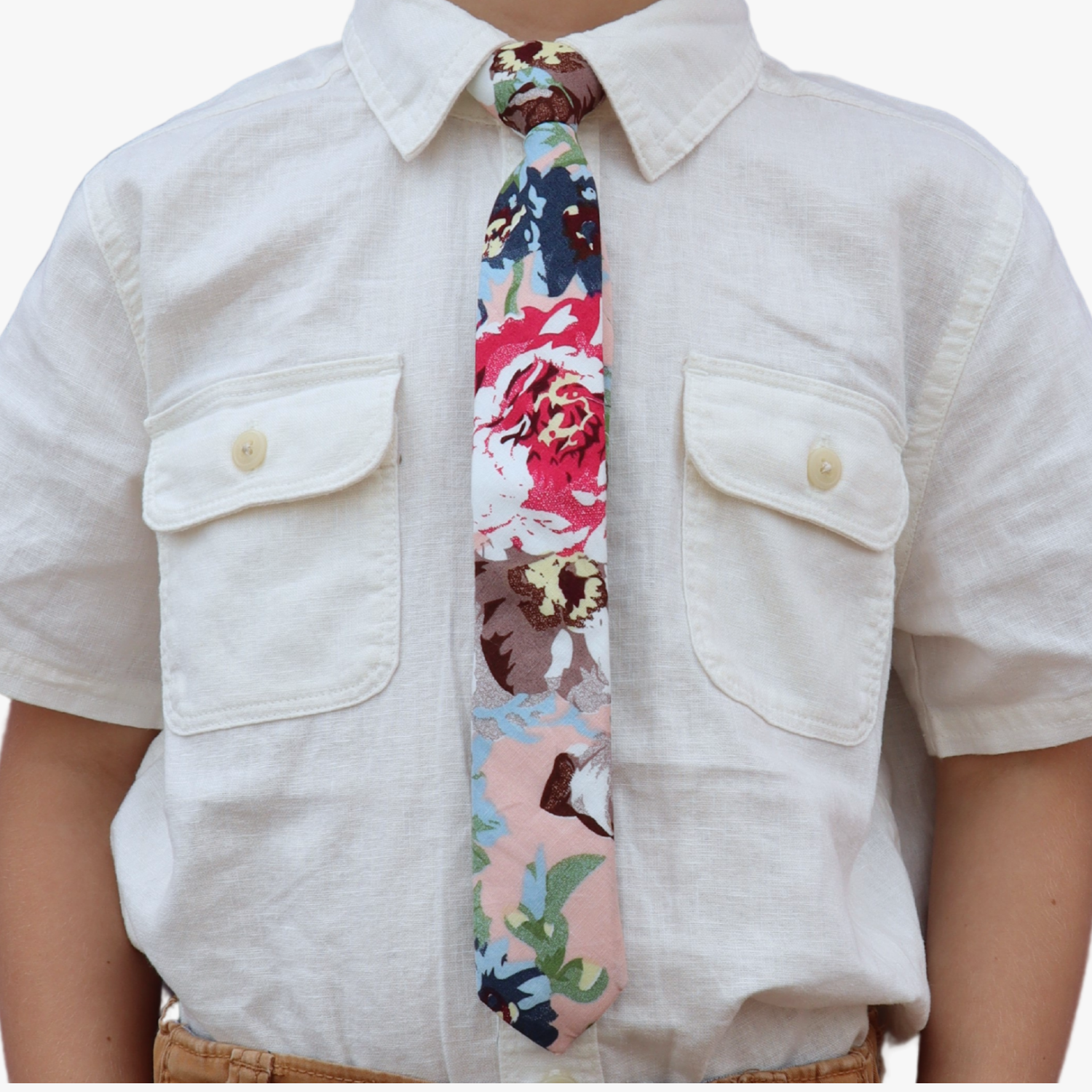 The torso of a boy wearing a floral kids tie with dark blue flowers, brown petals, and light green water leaves.