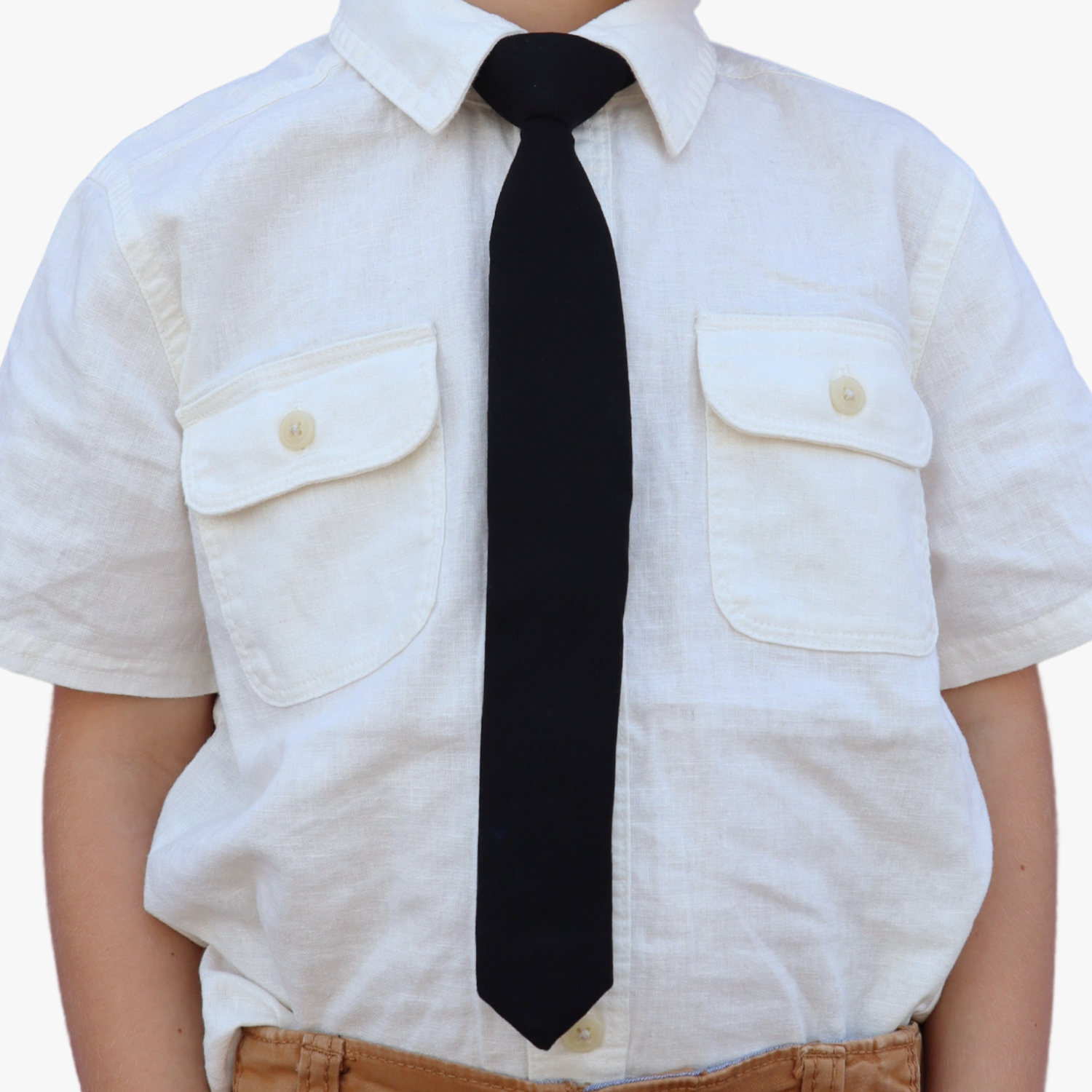 The torso of a boy wearing a solid kids tie with plain pitch black color.