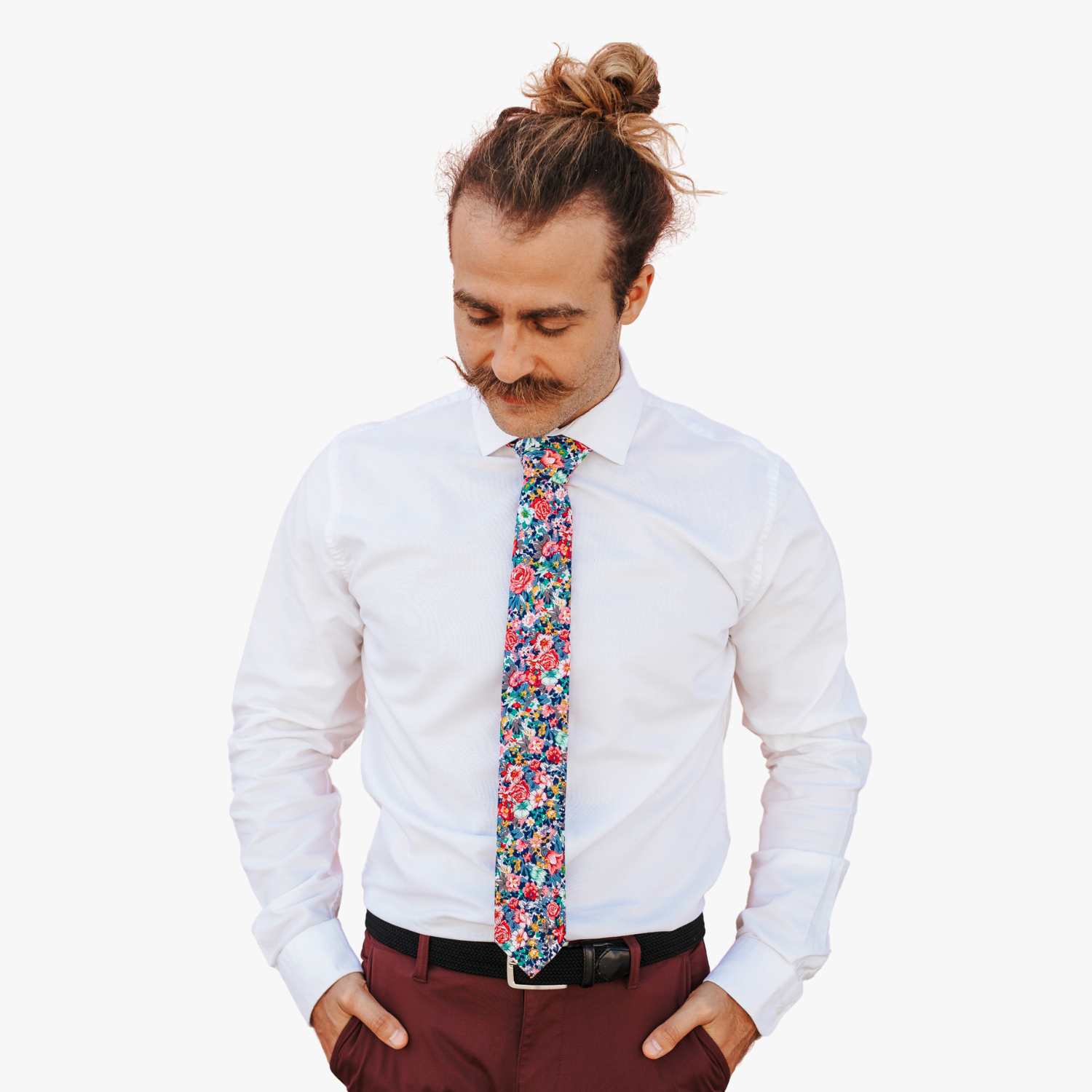 A man wearing a floral tie with pink rose flowers, dark petals, orange and sage green blossoms and blue and navy leaves.