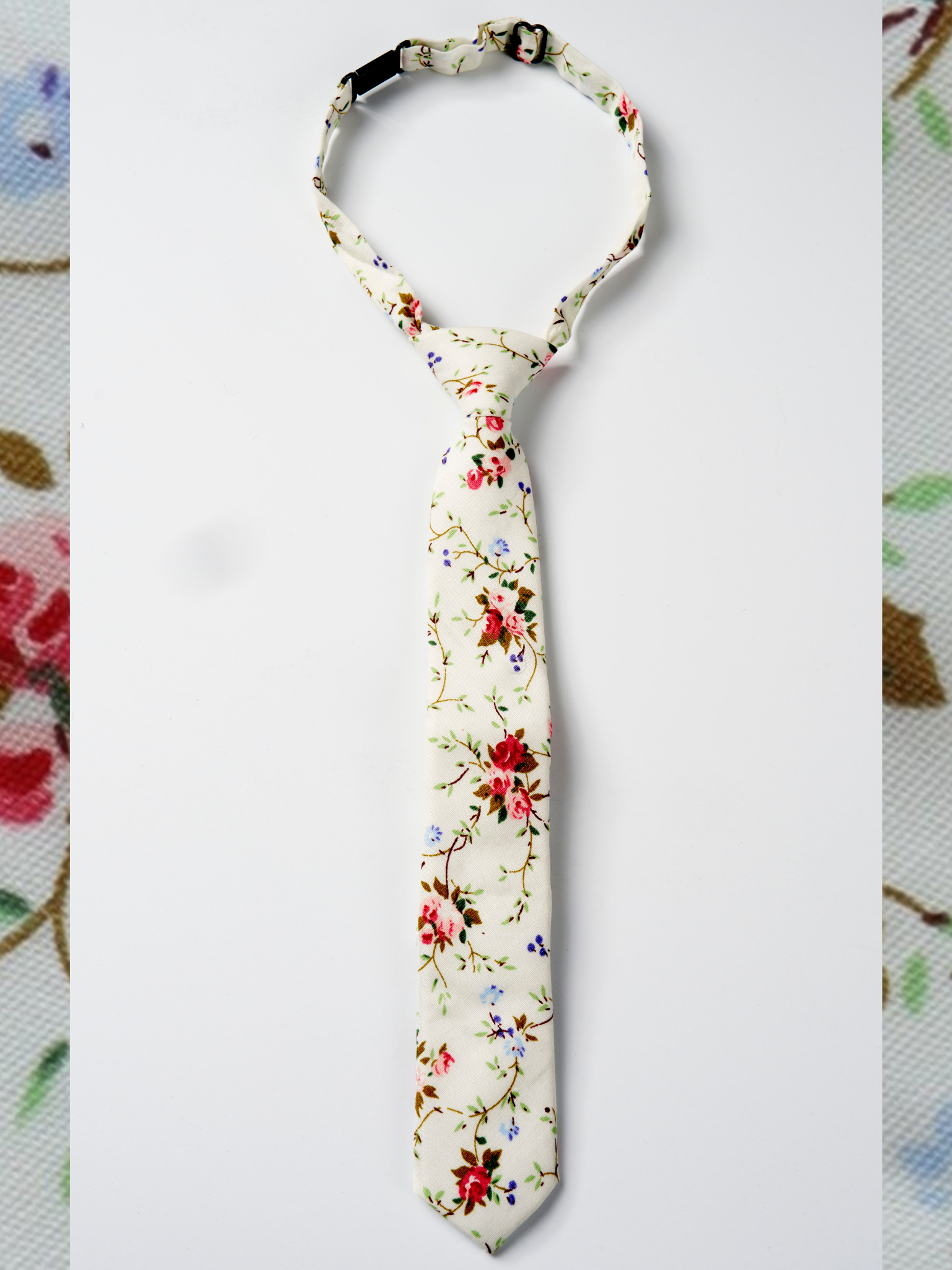 A folded woven cotton, floral men's tie with red flowers, pink petals, Christmas blossoms and green leaves.