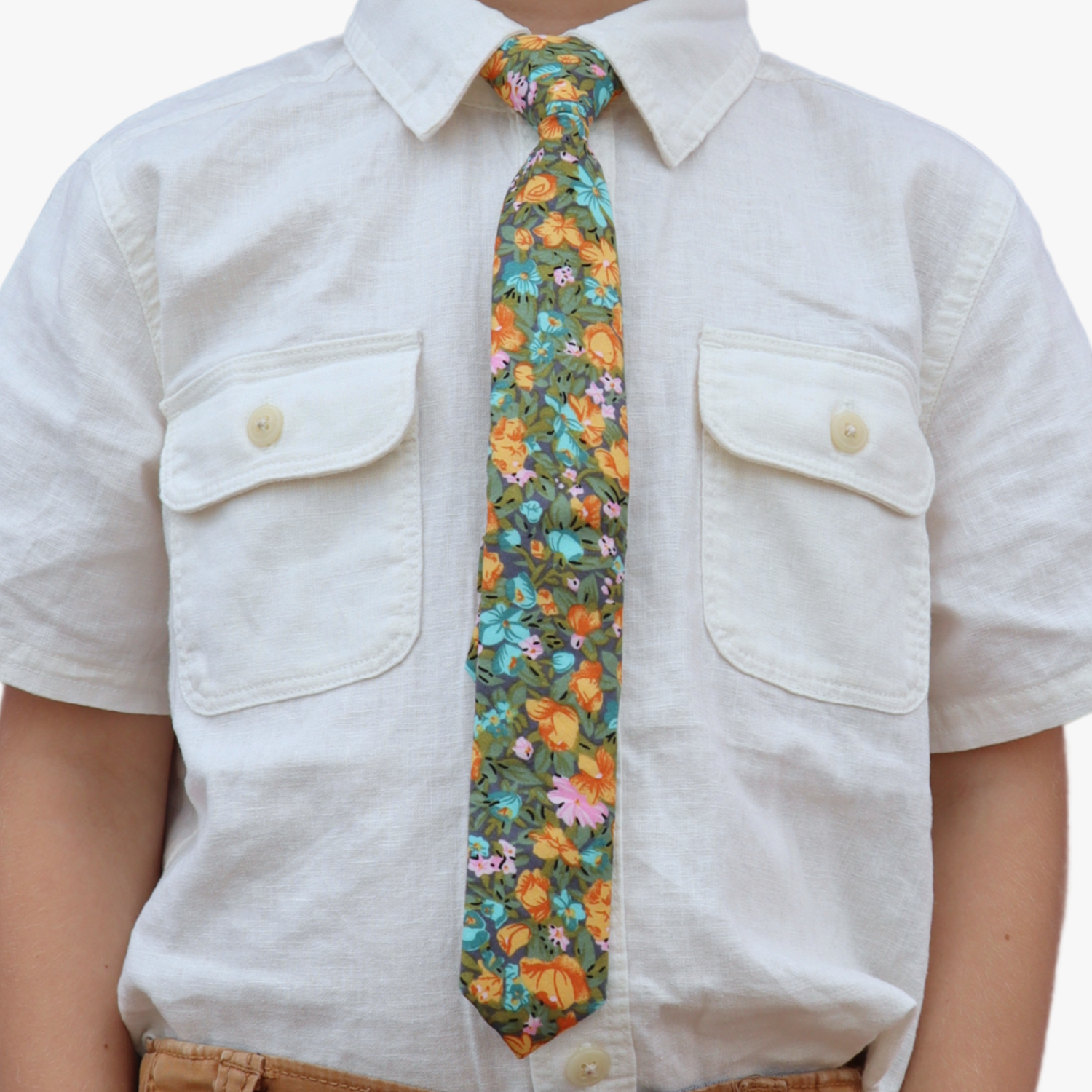 The torso of a boy wearing a floral kids tie with orange flowers, dark pletals, light blue blossoms and green leaves.