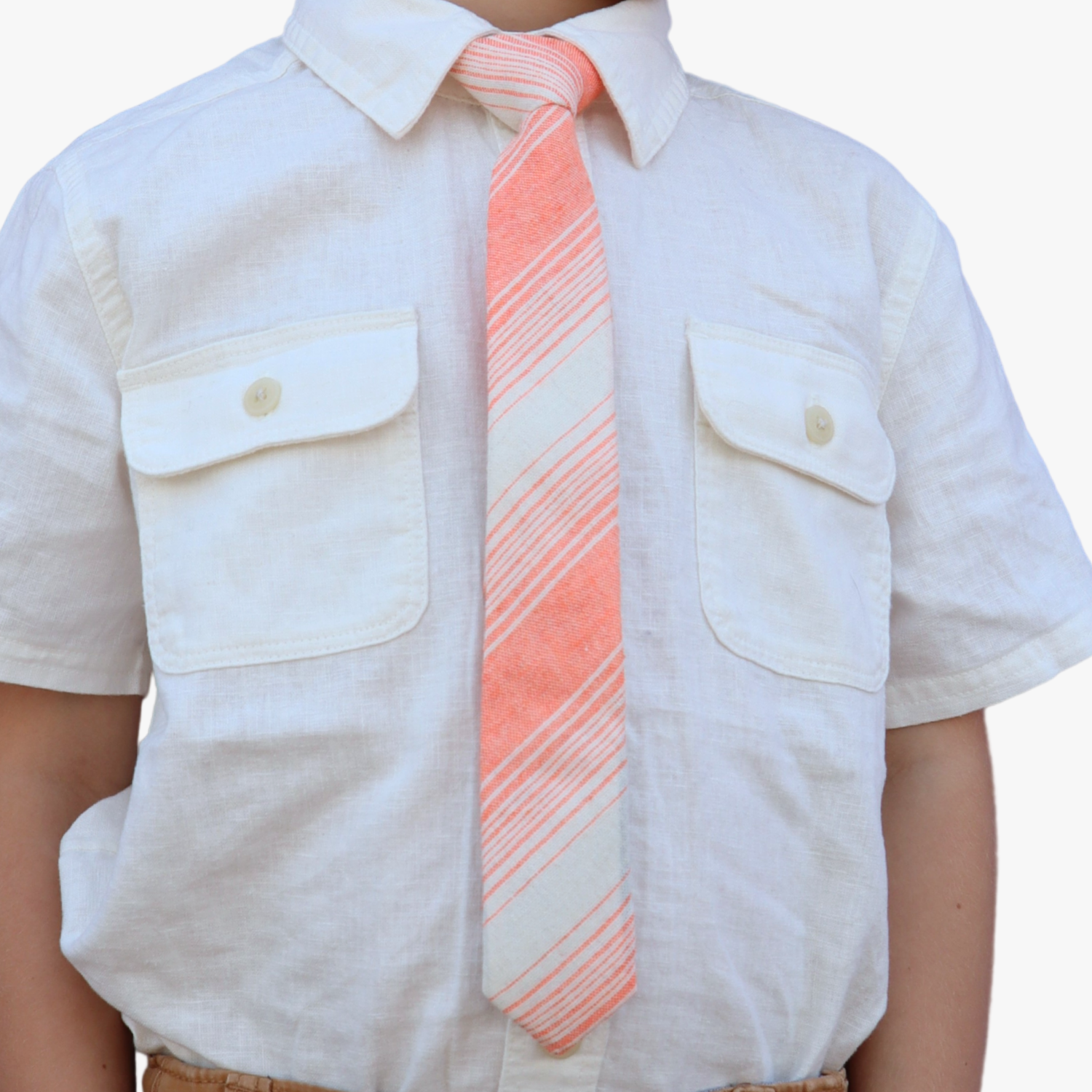 The torso of a boy wearing a striped kids tie with orange stripes, thin beige cream lines,  and off-white diagonal designs.