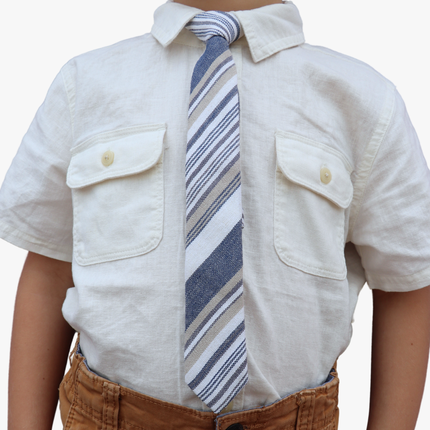 The torso of a boy wearing a striped kids tie with thin dark blue stripes, white lines, gold bars and diagonal designs.