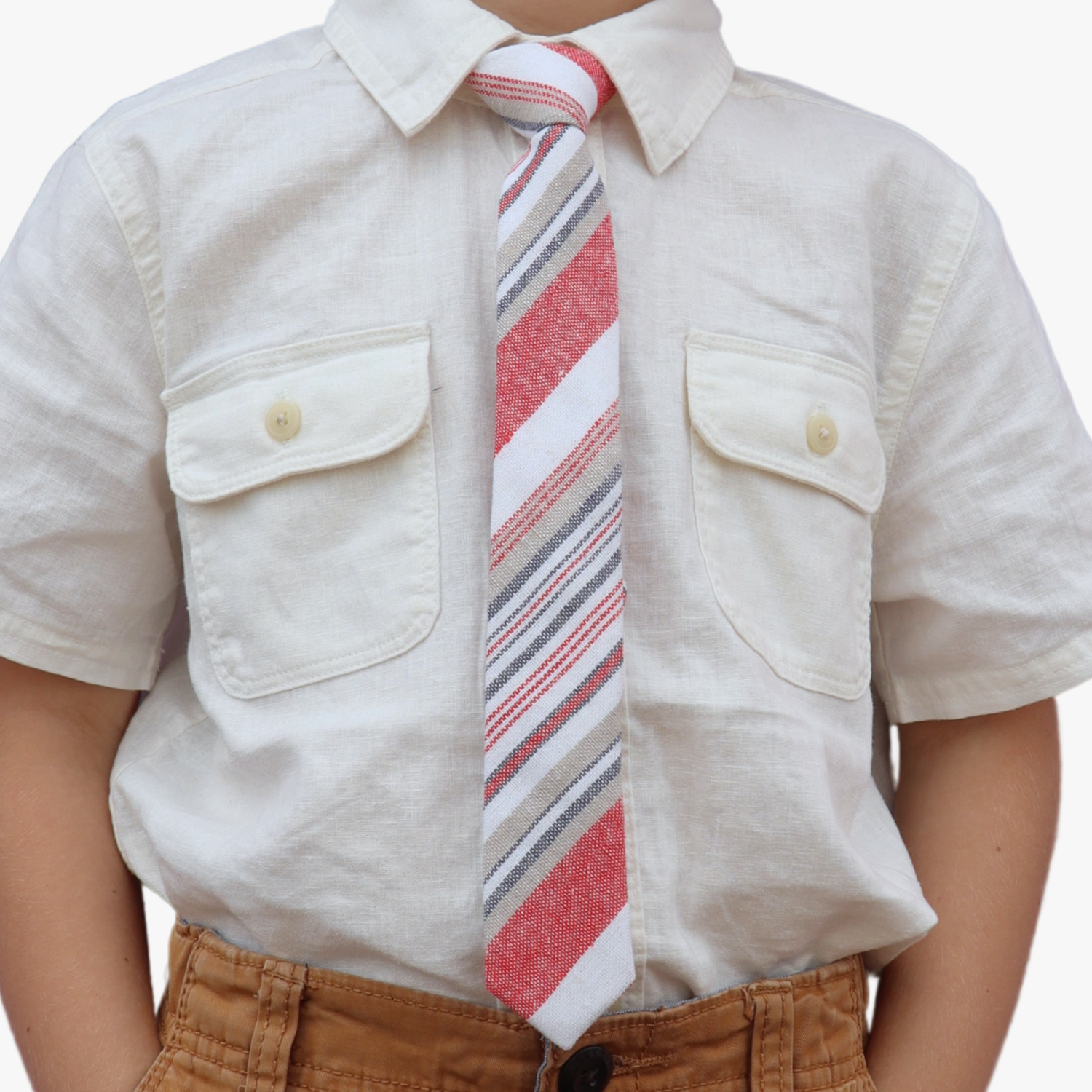 The torso of a boy wearing a striped kids tie with blood red stripes, white lines, gold bars and diagonal designs.