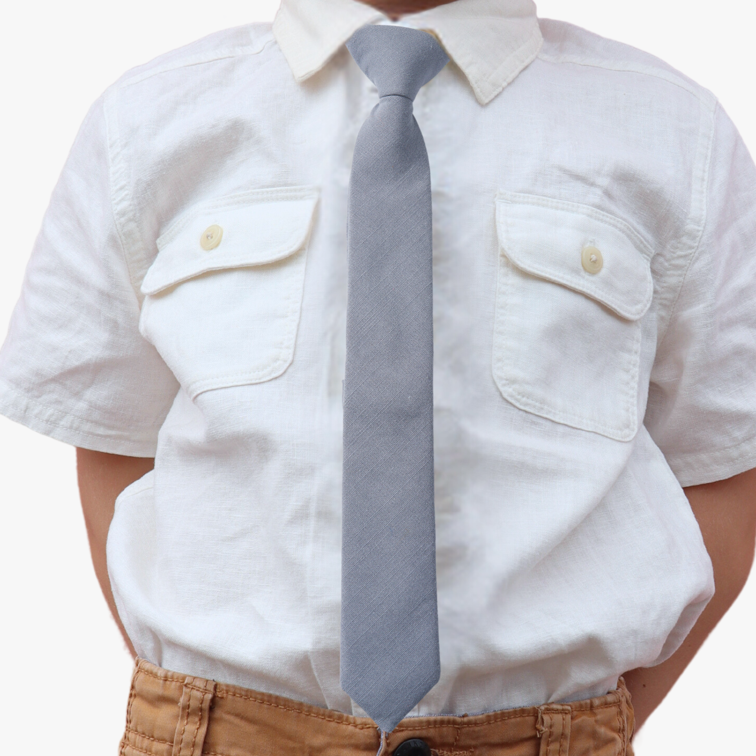 The torso of a boy wearing a solid kids tie with plain neutral light gray-blue color.