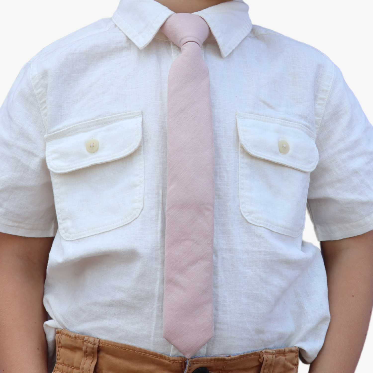 The torso of a boy wearing a solid kids tie with plain neutral pink taupe color.