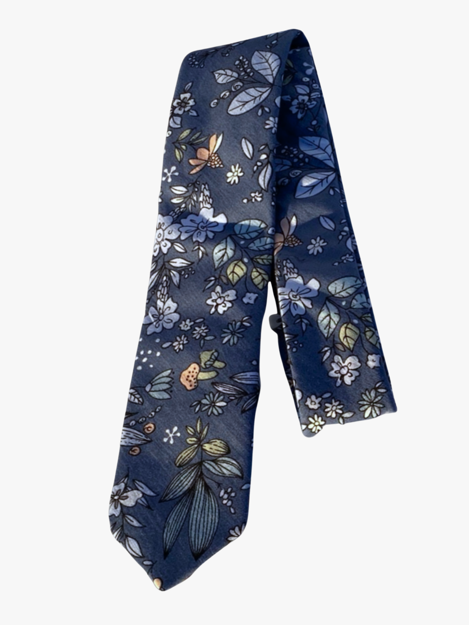 A folded floral adult men's necktie with deep blue fabric, pale blue flowers, light green leaves, pink cartoonish mushrooms.