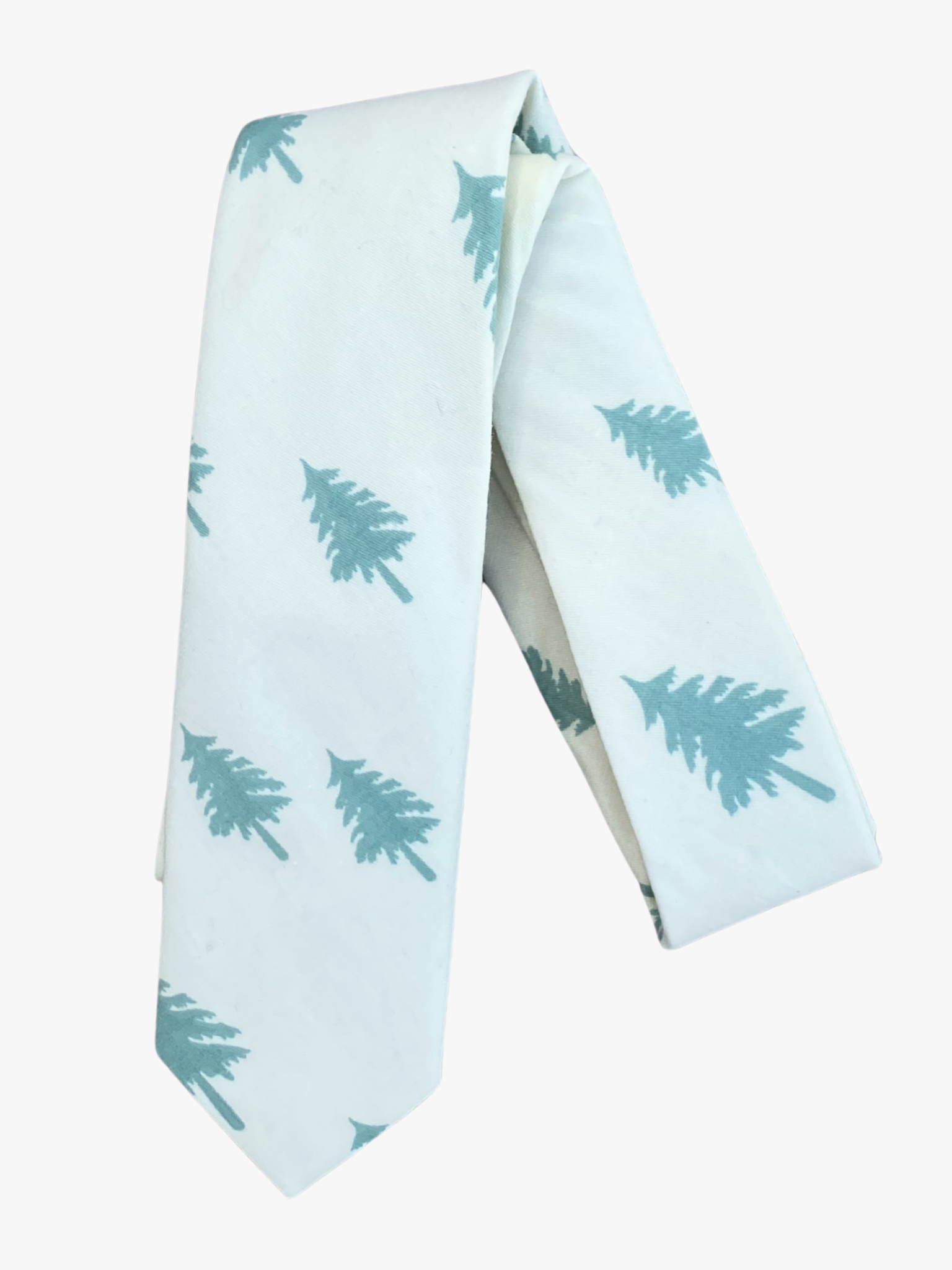 A folded Christmas tree adult men's necktie with pale jade green pine trees silhouette on a snowy white fabric.