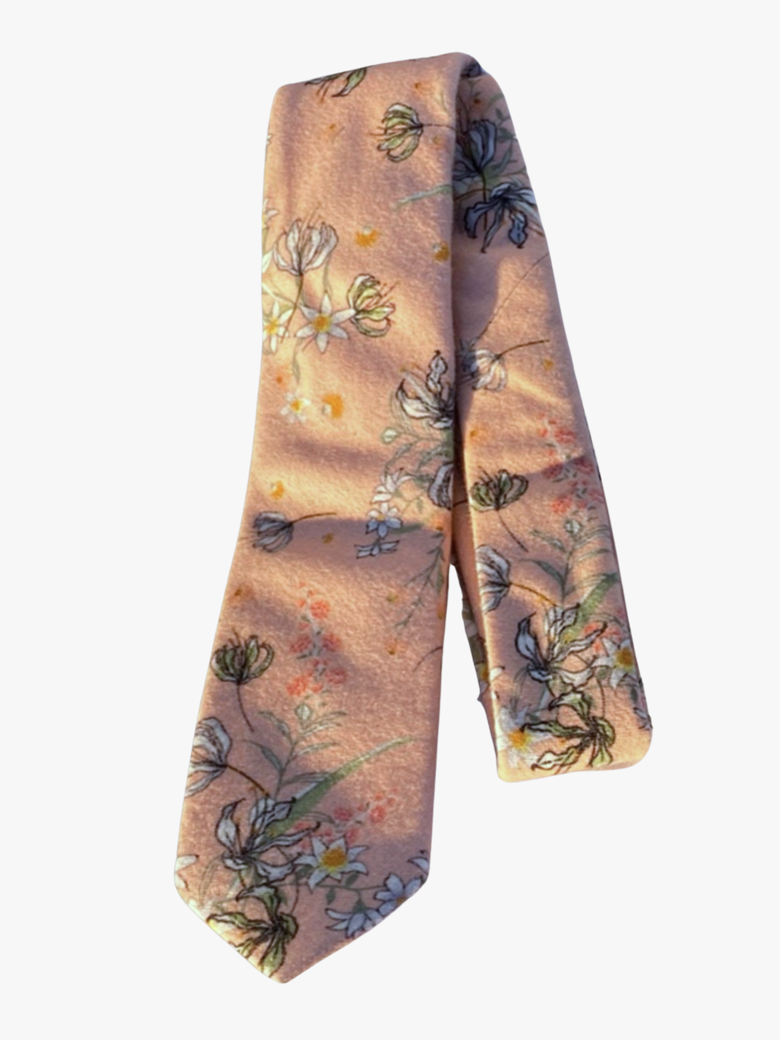 A folded floral adult men's necktie with light salmon fabric, yellow, white, pink, and black flowers, and green leaves.