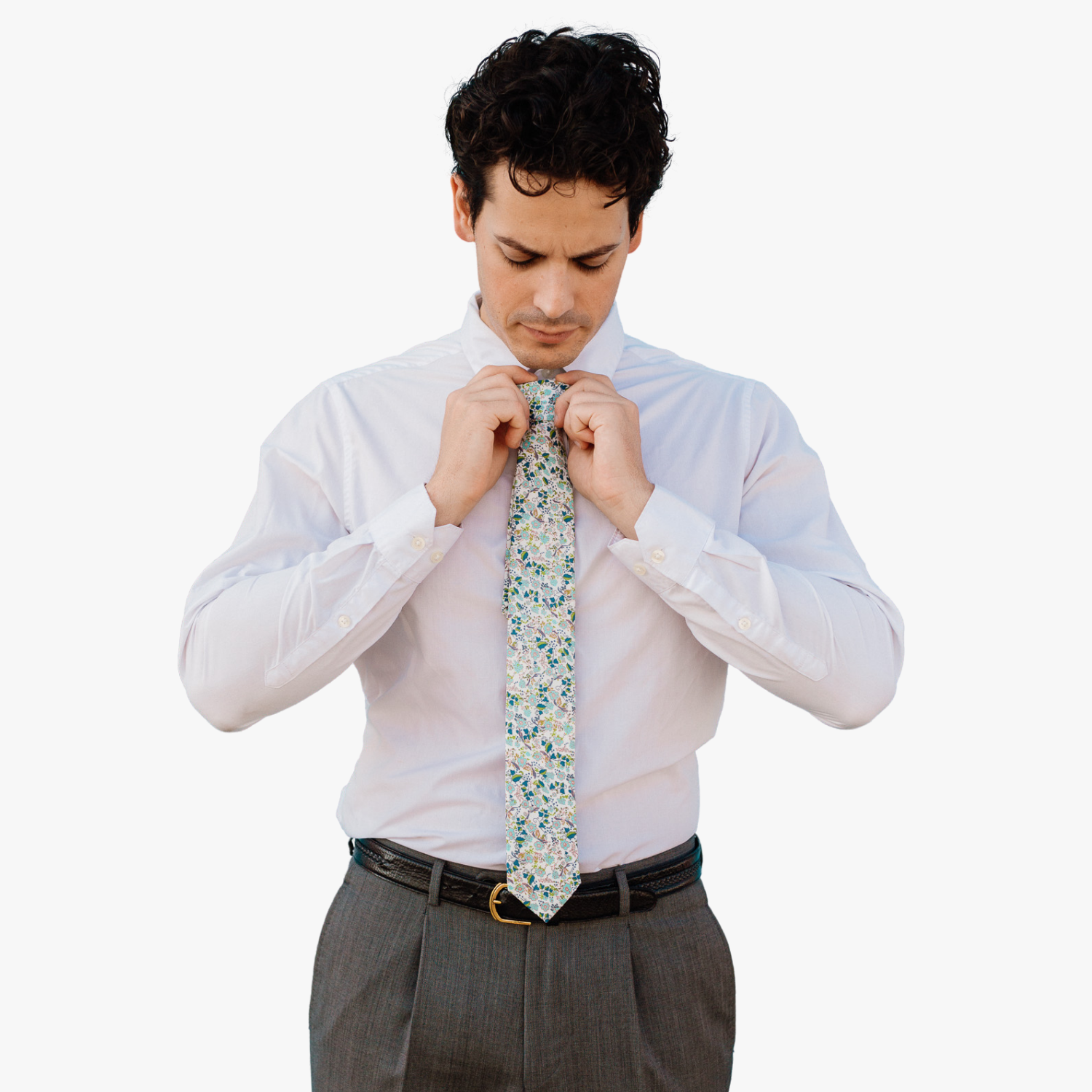 A man wearing a floral tie with  dusty blue flowers, pink centers, turquoise blossoms and bluish green leaves.