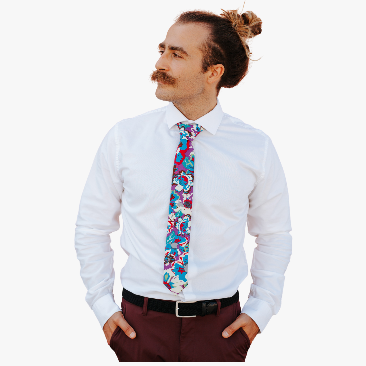 A man in dress clothes wearing a floral tie with white flowers, blue petals, purple blossoms and light green leaves.