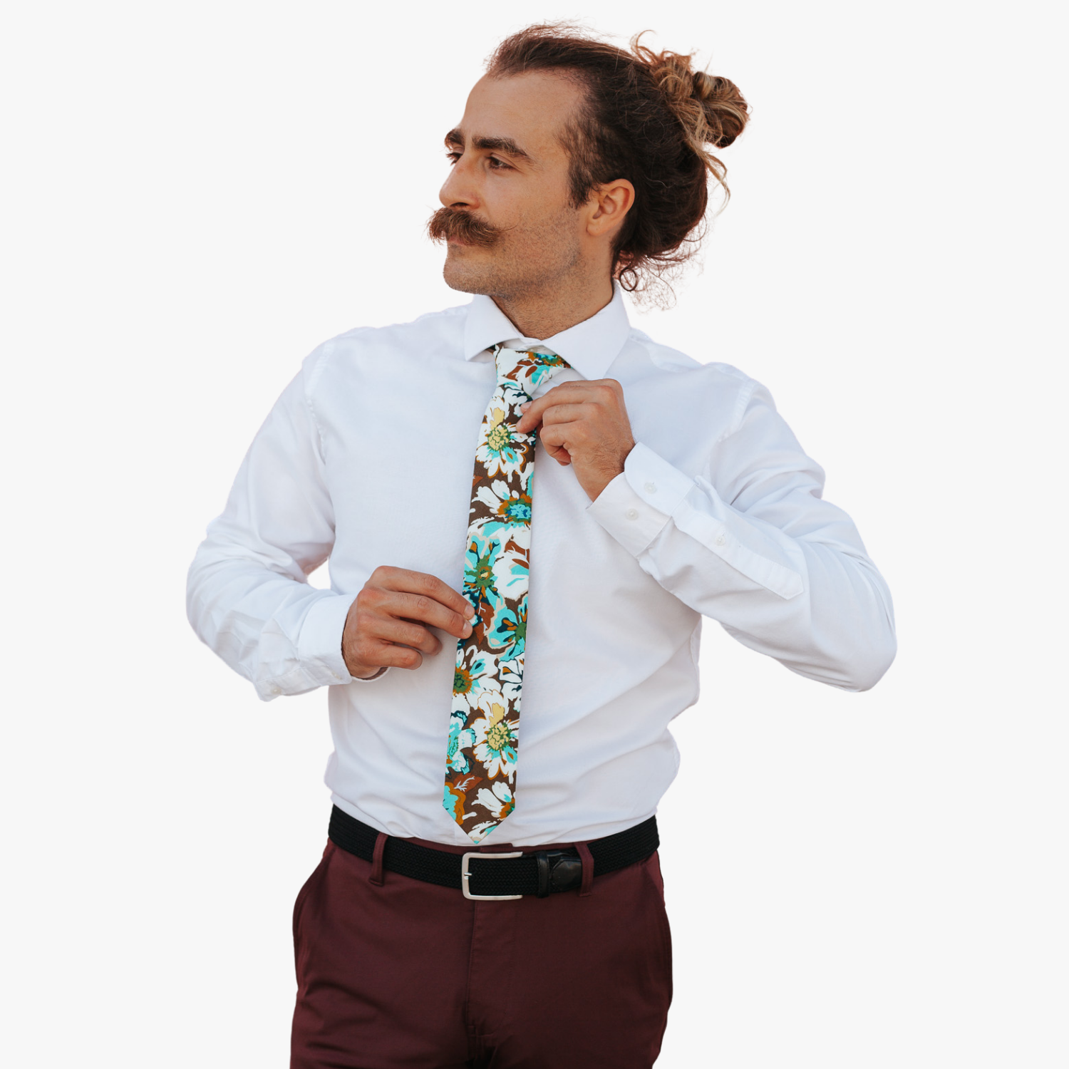 A man in dress clothes wearing a floral tie with white flowers, pale blue petals, yellow blossoms and brown leaves on brown.
