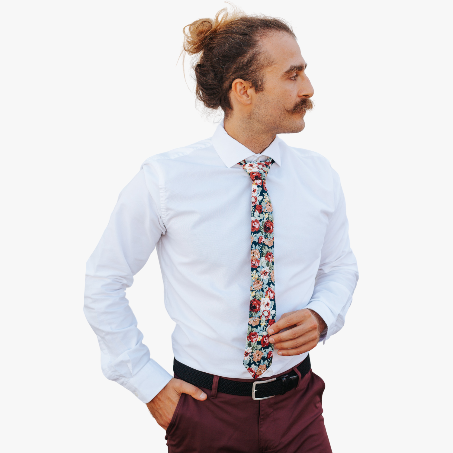 A man wearing a floral tie with  dark red flowers, burnt orange petals, rose blossoms and light green leaves.
