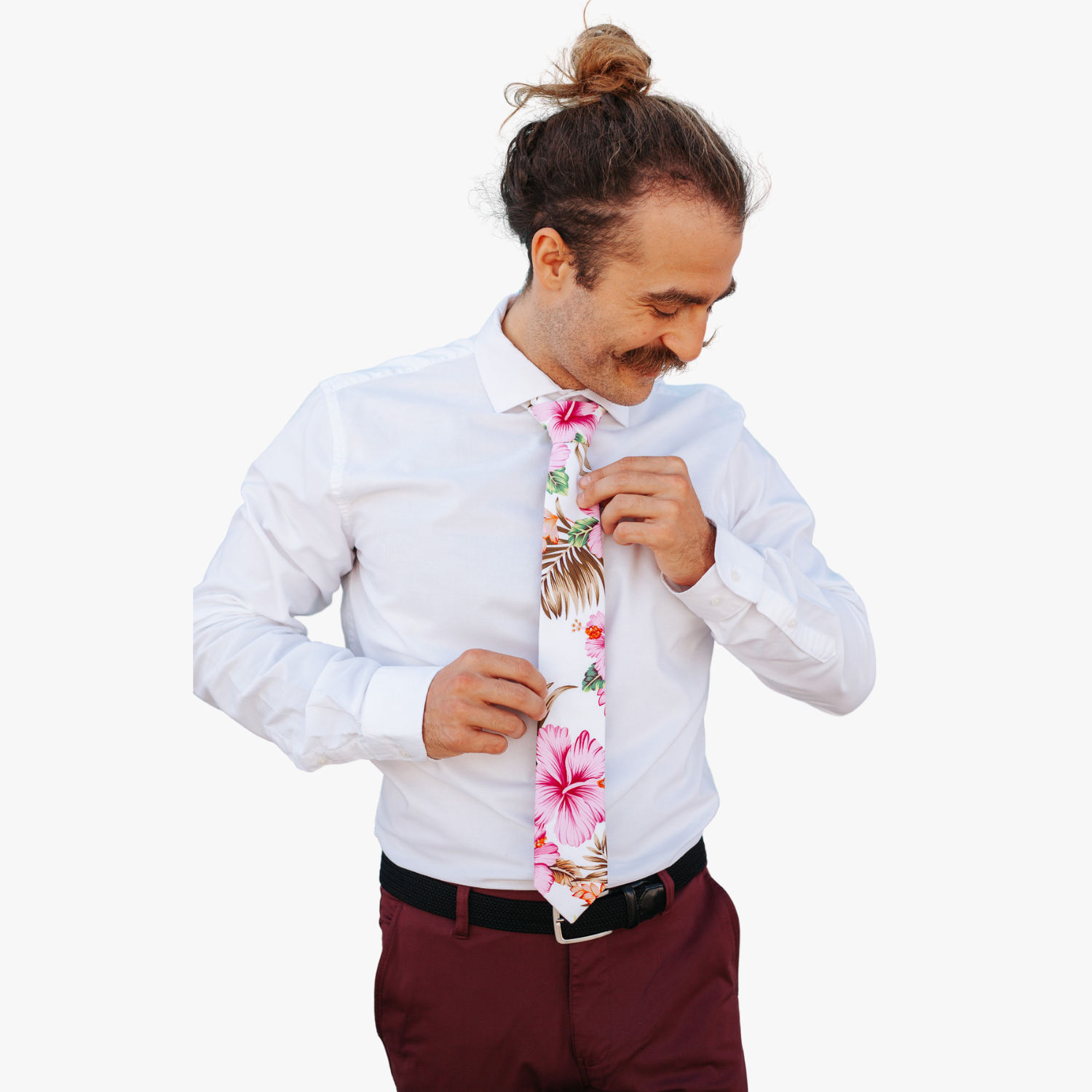 A man wearing a floral tie with pink hibiscus flowers, Hawaii petals, spots of green and orange, and brown leaves.