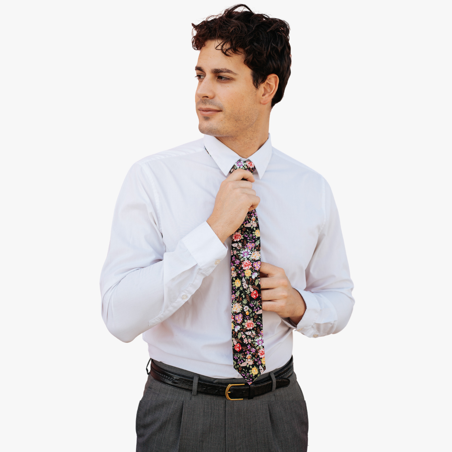 A man in dress clothes wearing a floral tie with  pink flowers, yellow petals, wisteria purple blossoms and brown leaves.