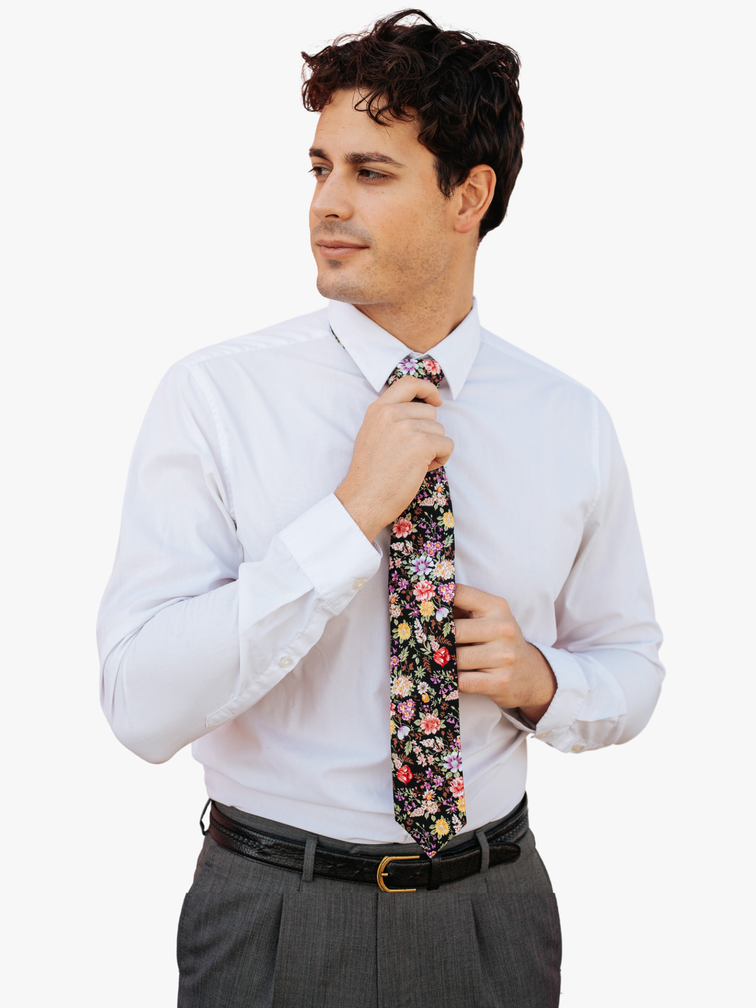 A man in dress clothes wearing a floral tie with  pink flowers, yellow petals, wisteria purple blossoms and brown leaves.