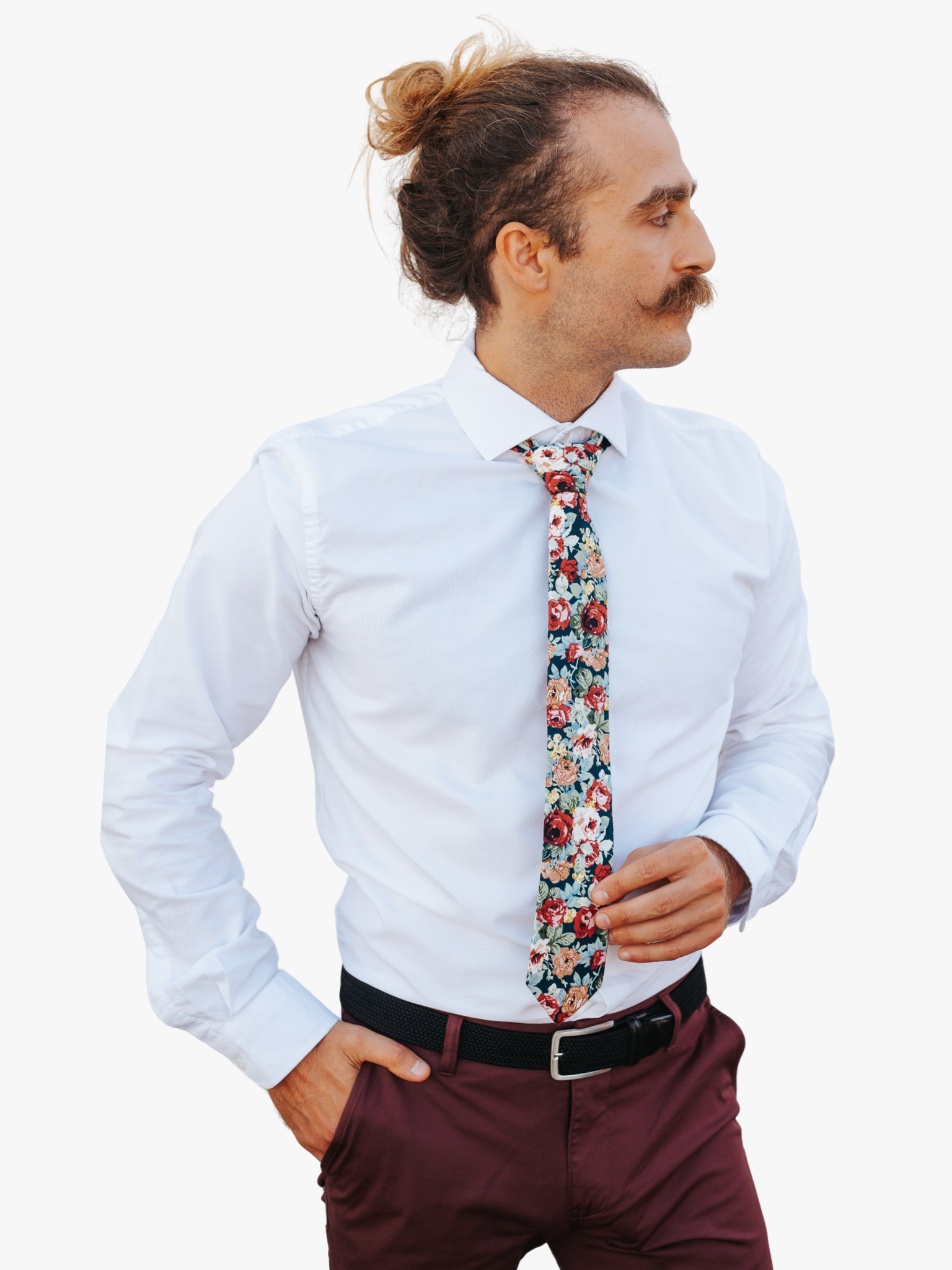 A man wearing a floral tie with  dark red flowers, burnt orange petals, rose blossoms and light green leaves.