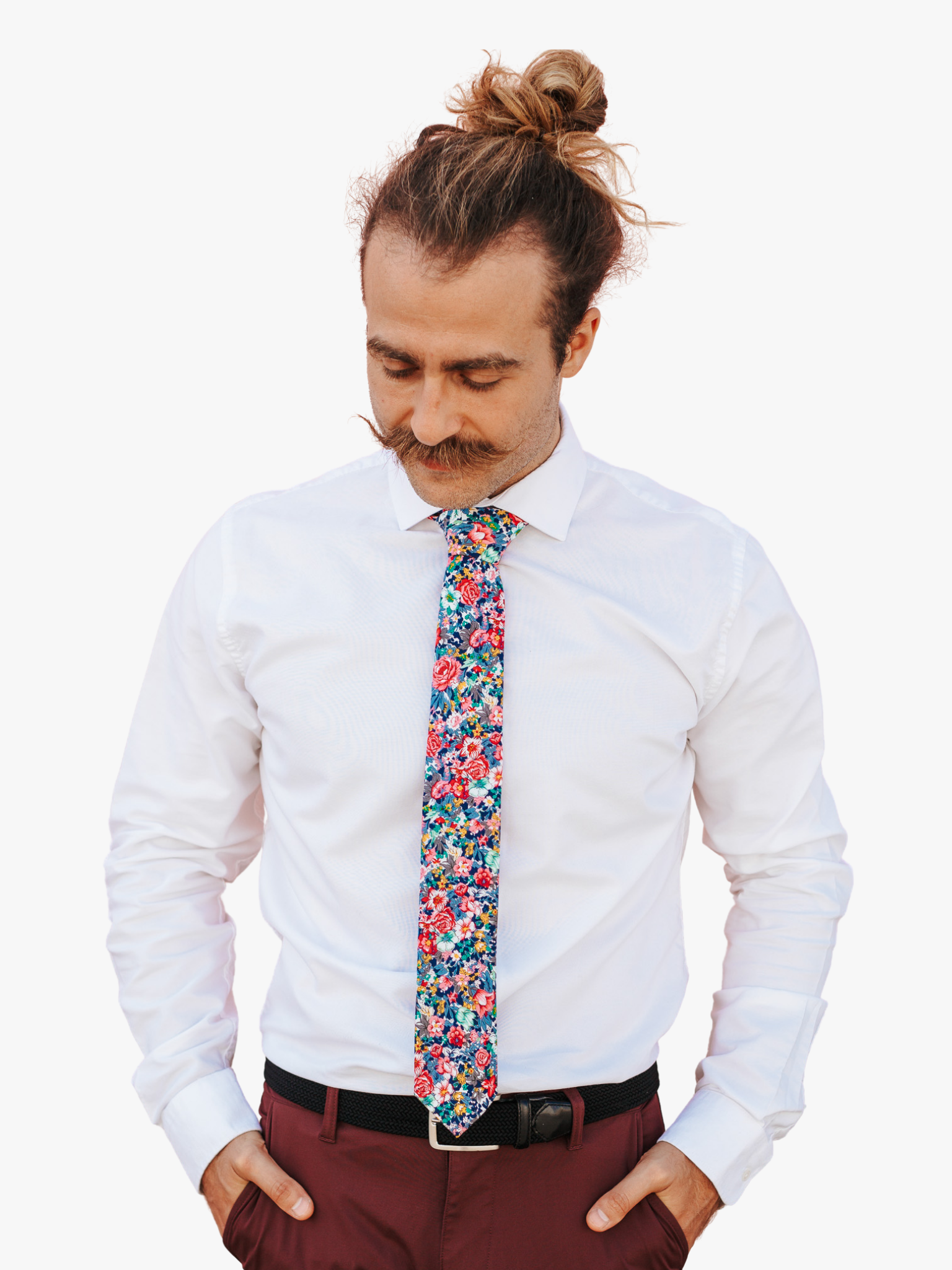 A man wearing a floral tie with pink rose flowers, dark petals, orange and sage green blossoms and blue and navy leaves.