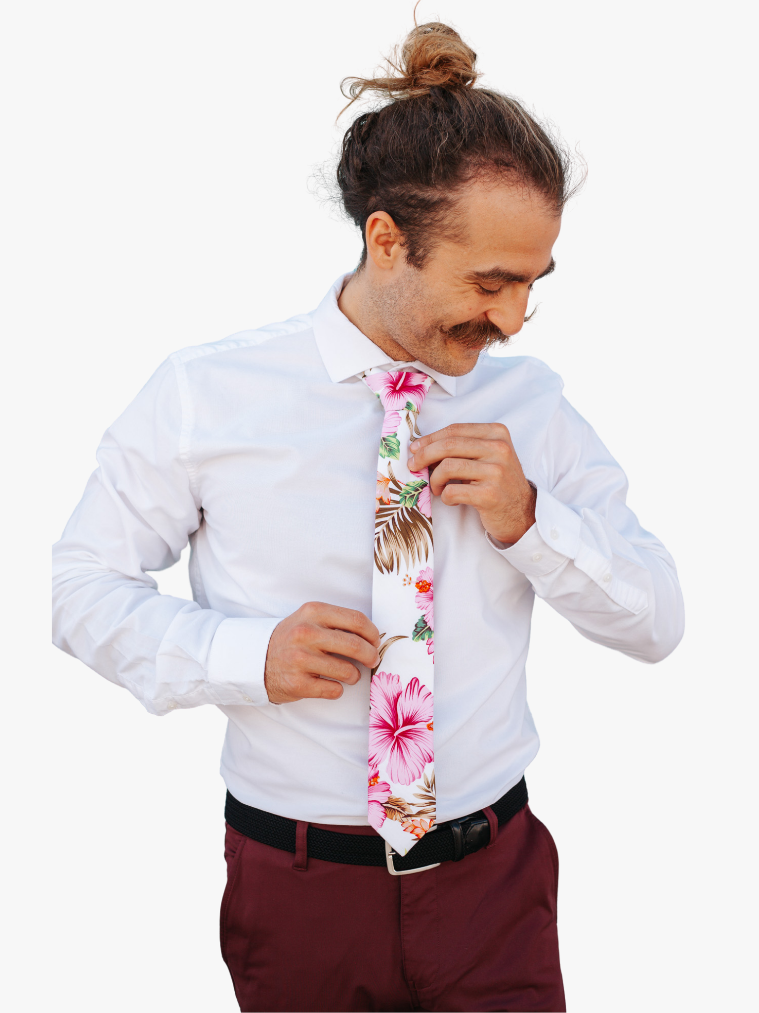 A man wearing a floral tie with pink hibiscus flowers, Hawaii petals, spots of green and orange, and brown leaves.