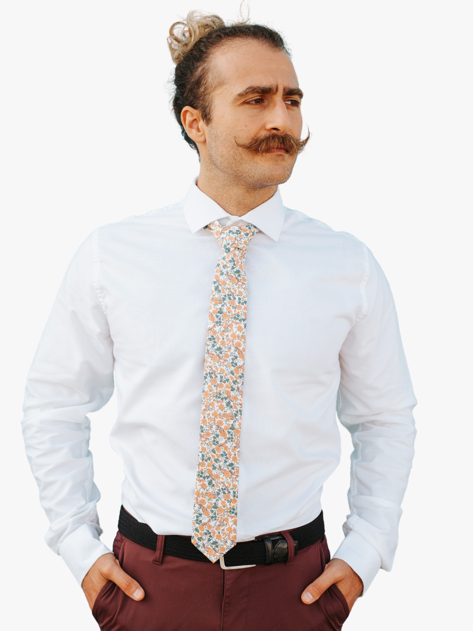 A man in dress clothes wearing a floral tie with orange wild flowers, blue petals, and green leaves.