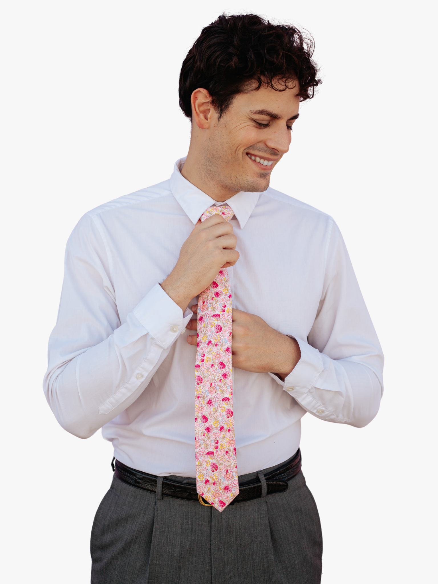 A man wearing a floral tie with pink berry flowers, dark petals, yellow blossoms, and pastel leaves on light rose fabric.