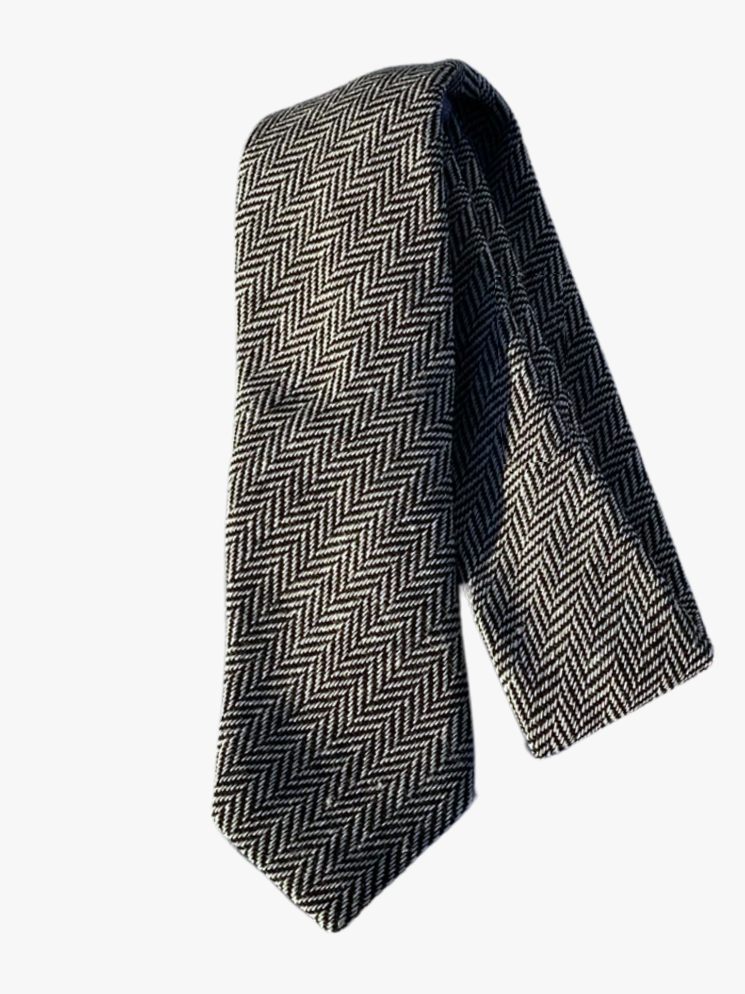 A folded herringbone adult men's necktie with alternating black and white arrows designs on a soft cotton fabric.