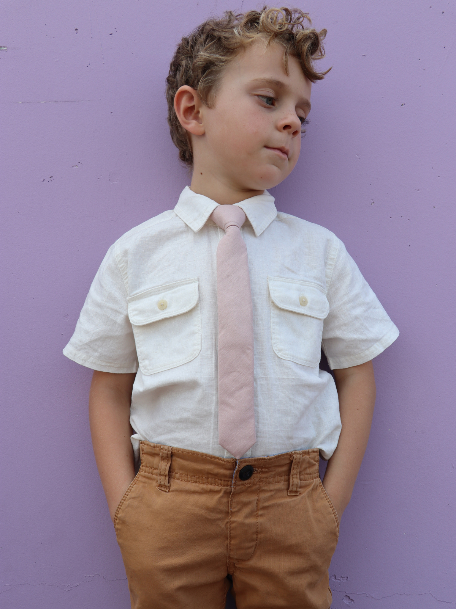 A boy in a white shirt with a neutral taupe solid colored pre tied tie for kids ages 1-12 available in 4 childrens sizes.