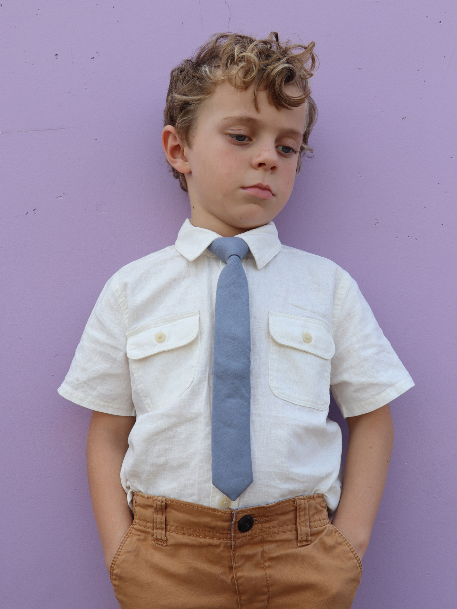 A boy in a white shirt with a deep cobalt blue solid colored pre tied tie for kids ages 1-12 available in 4 childrens sizes.