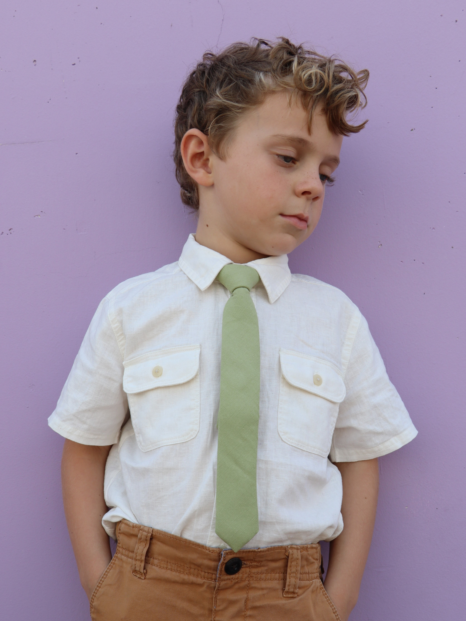 A boy in a white shirt with a light green solid colored pre tied tie for kids ages 1-12 available in 4 childrens sizes.