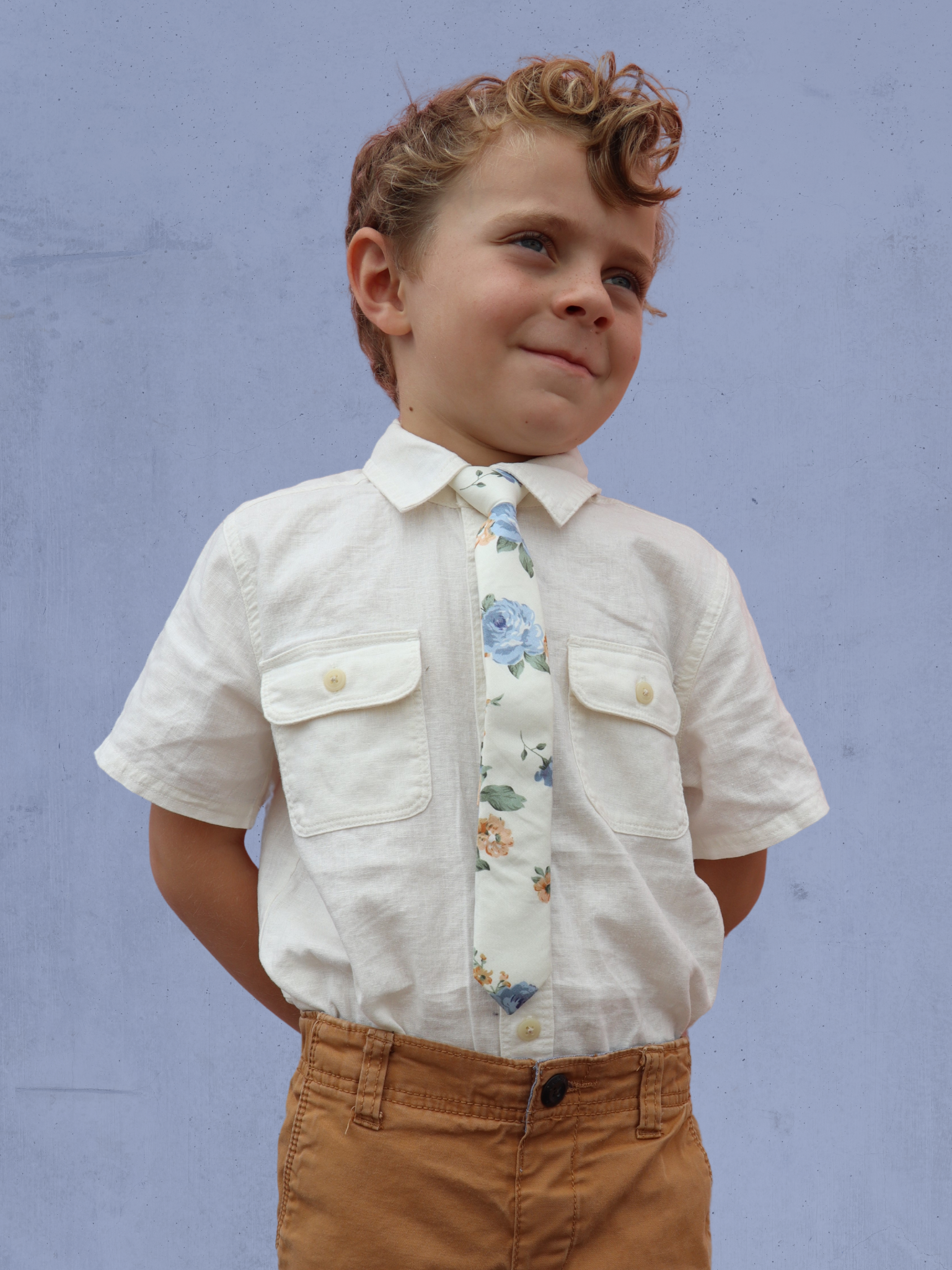 A boy in a white shirt with a beige and blue floral pre tied tie for kids ages 1-12 available in 4 childrens sizes.