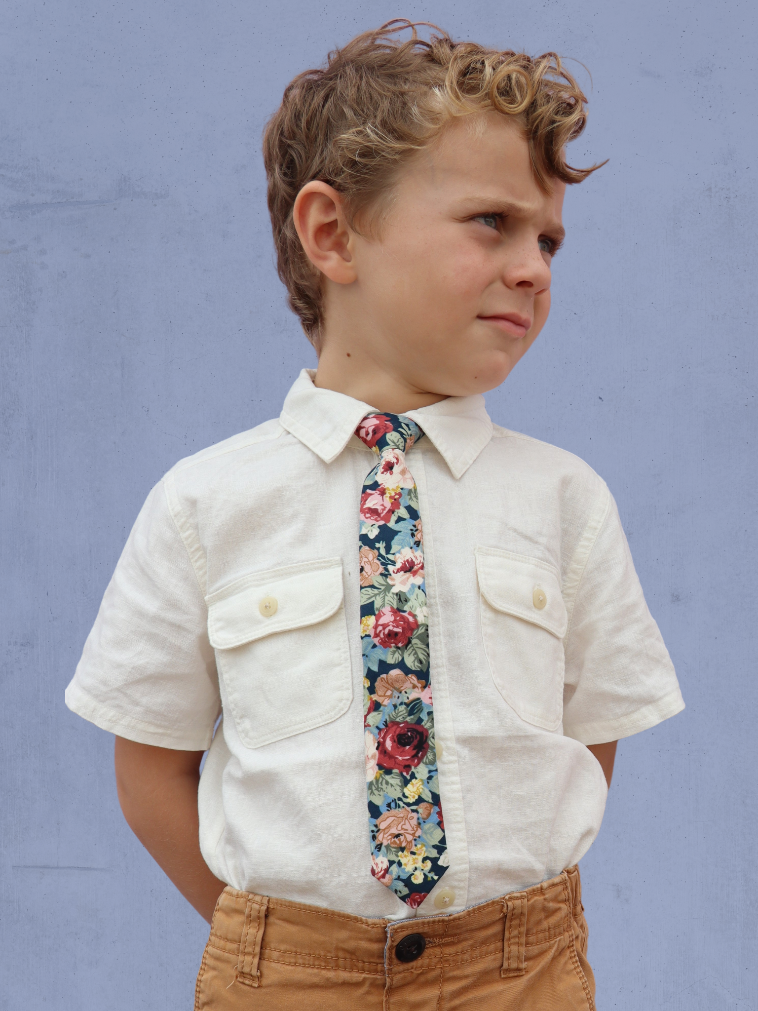 A boy in a white shirt with a navy and red floral pre tied tie for kids ages 1-12 available in 4 childrens sizes.