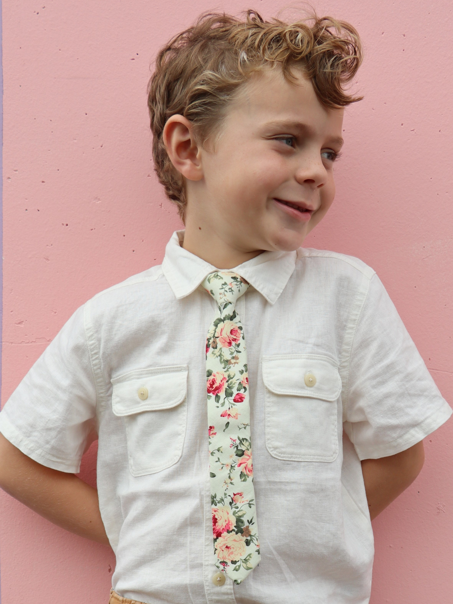 A boy in a white shirt with a mint and pink floral pre tied tie for kids ages 1-12 available in 4 childrens sizes.