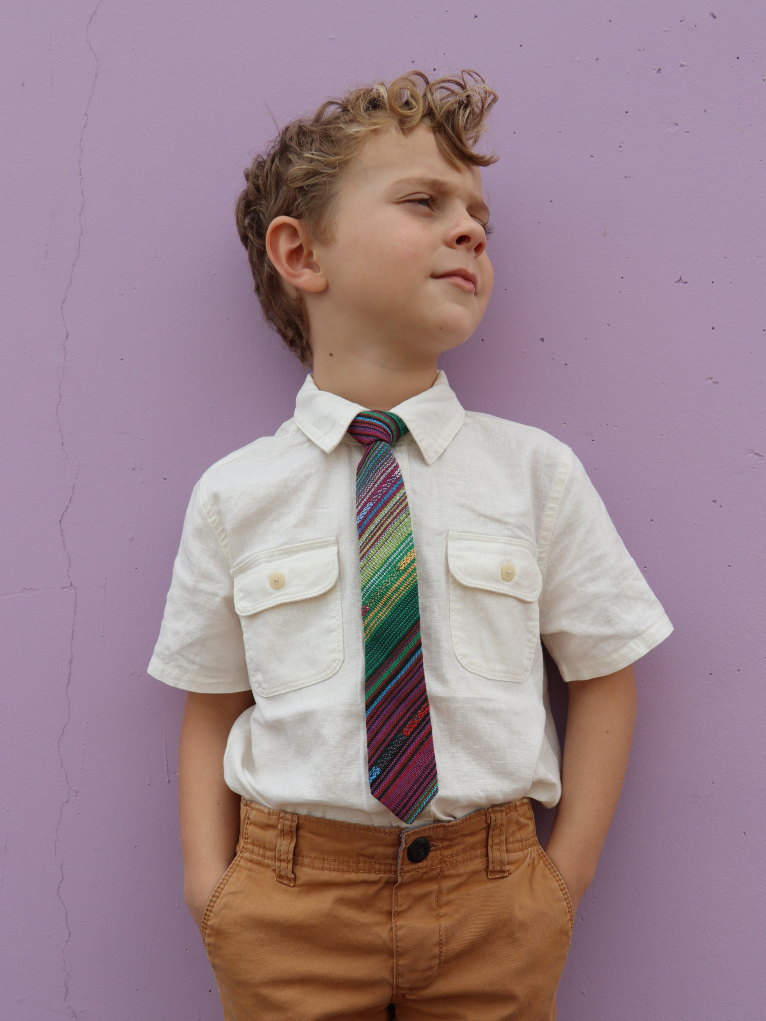 A boy in a white shirt with a green and purple striped pre tied tie for kids ages 1-12 available in 4 childrens sizes.