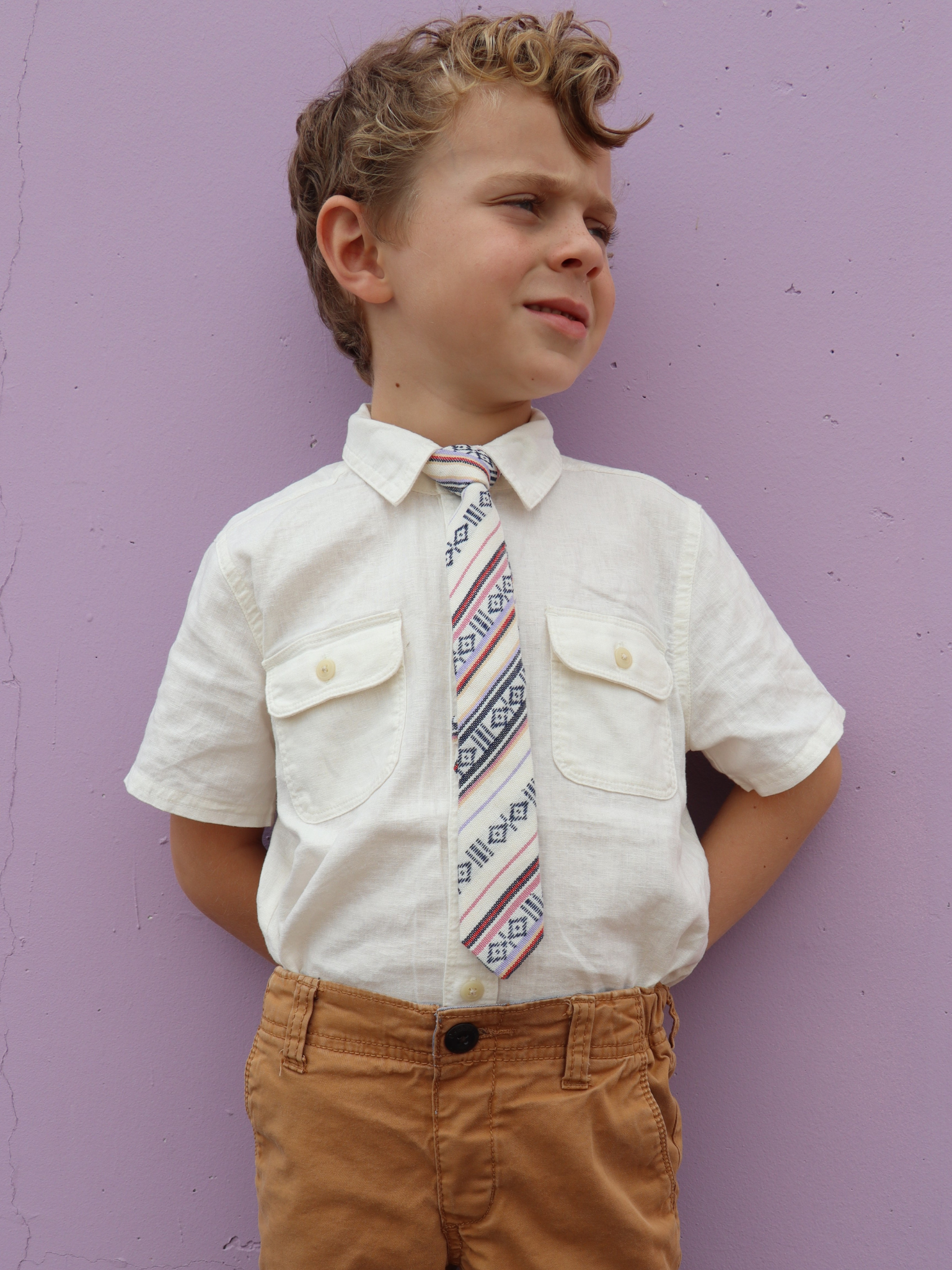 A boy in a white shirt with a white, red and black striped pre tied tie for kids ages 1-12 available in 4 childrens sizes.