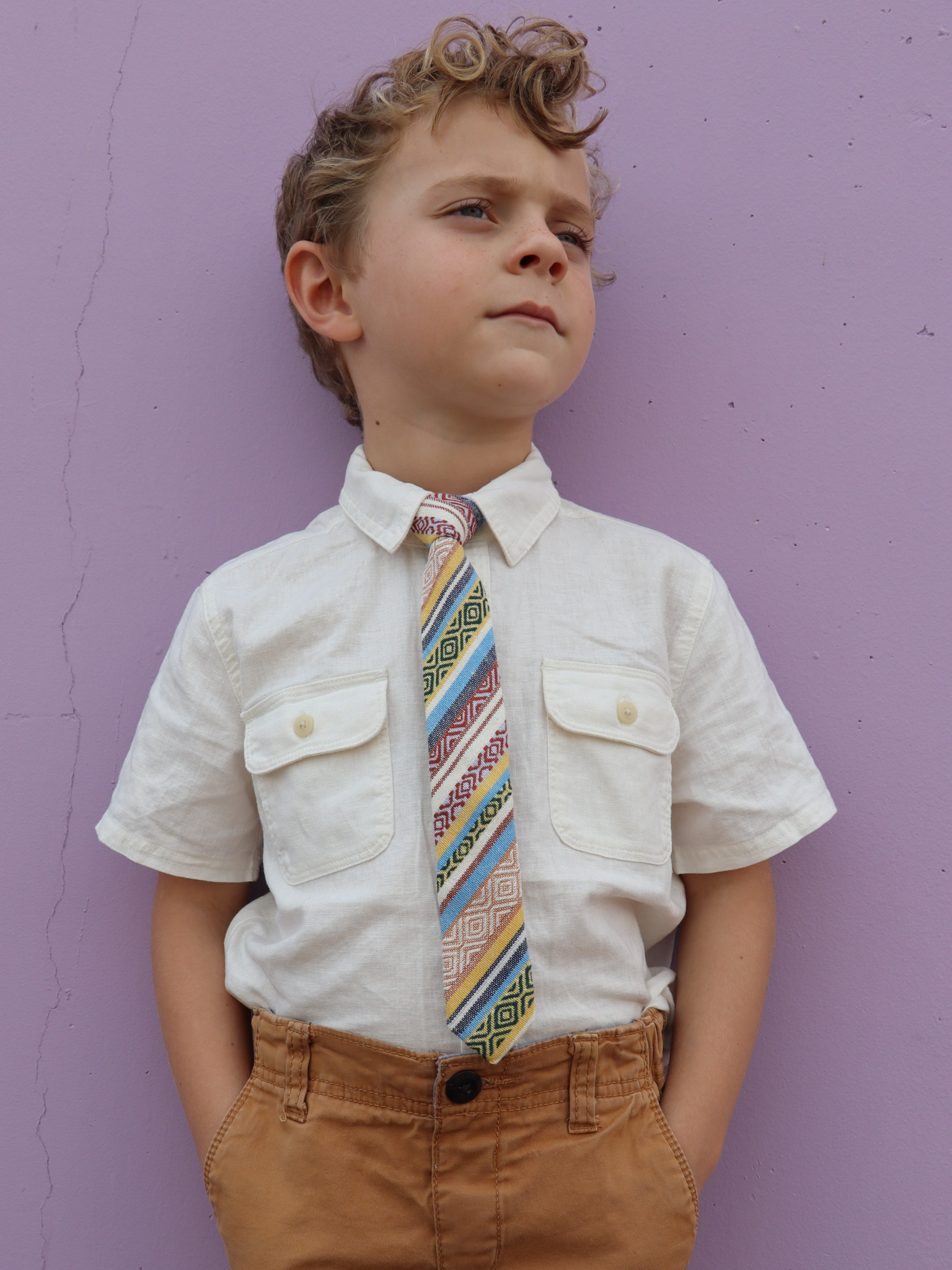 A boy in a white shirt with a yellow and blue striped pre tied tie for kids ages 1-12 available in 4 childrens sizes.