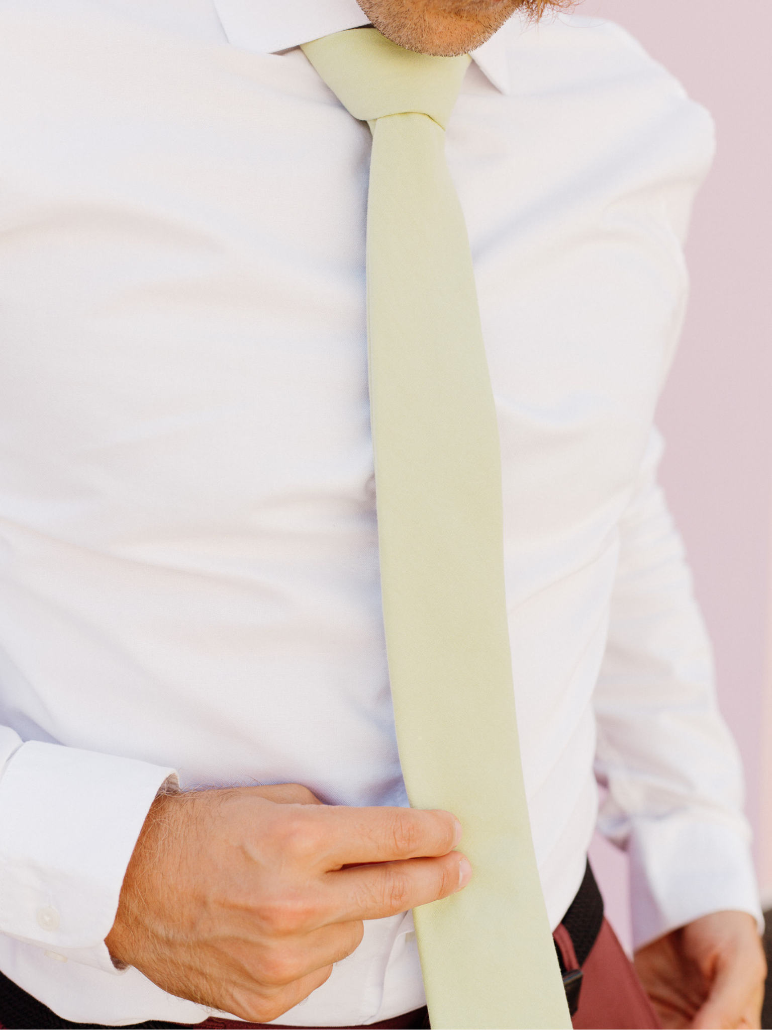 A close up of a man wearing a sage green solid-colored cotton skinny tie for weddings, grooms, and groomsmen.