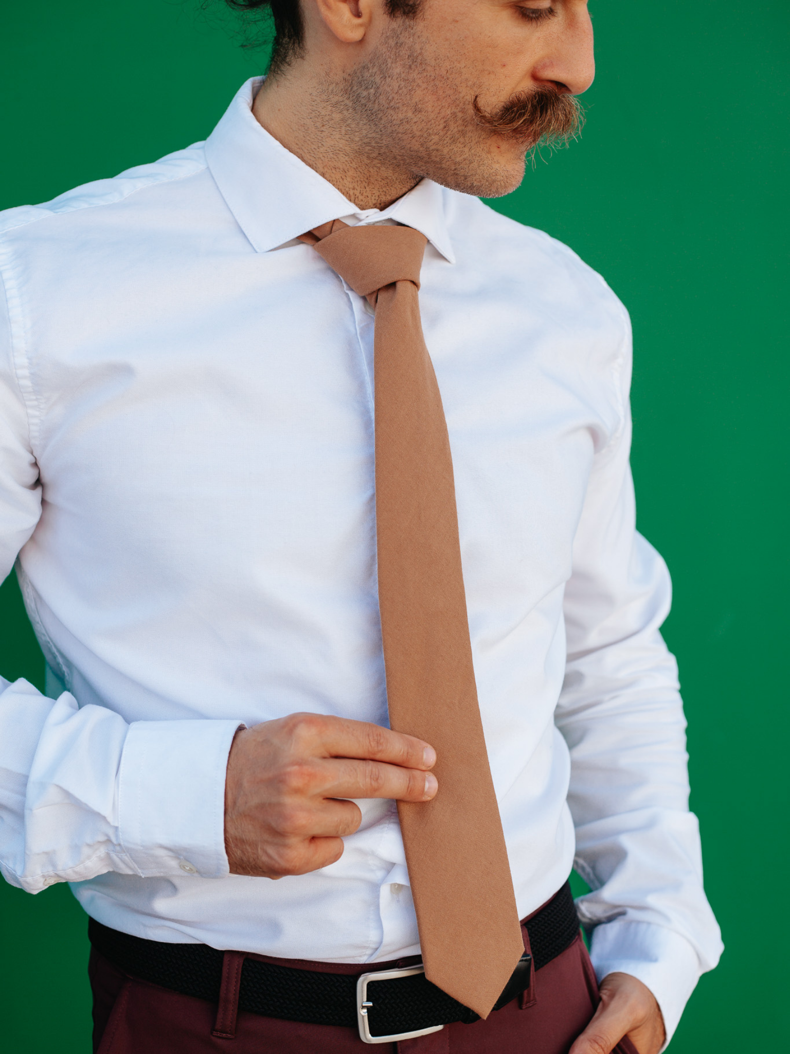 A close up of a man wearing a light taupe brown solid-colored cotton skinny tie for weddings, grooms, and groomsmen.