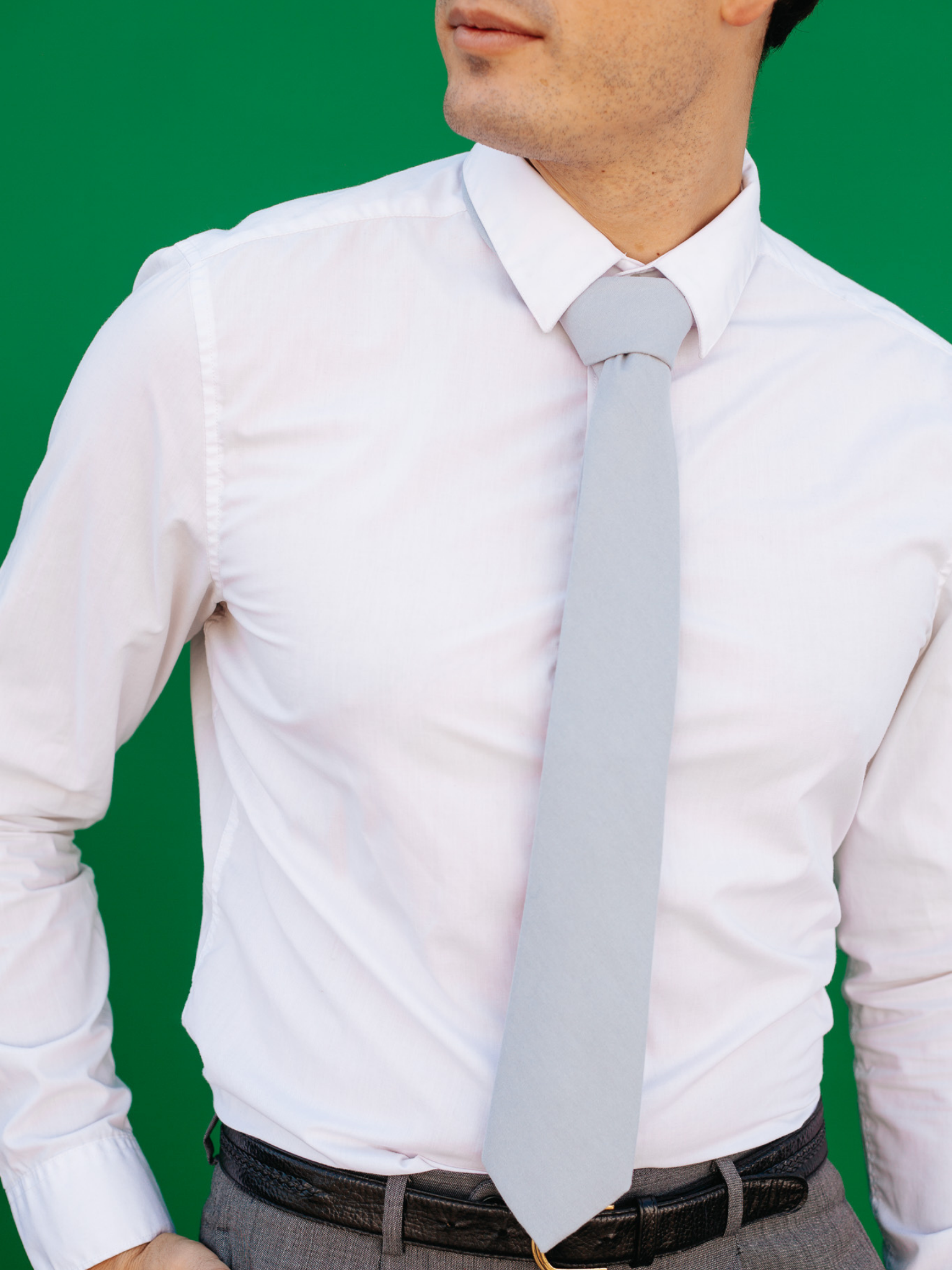 A close up of a man wearing a pale blue/gray solid-colored cotton skinny tie for weddings, grooms, and groomsmen.