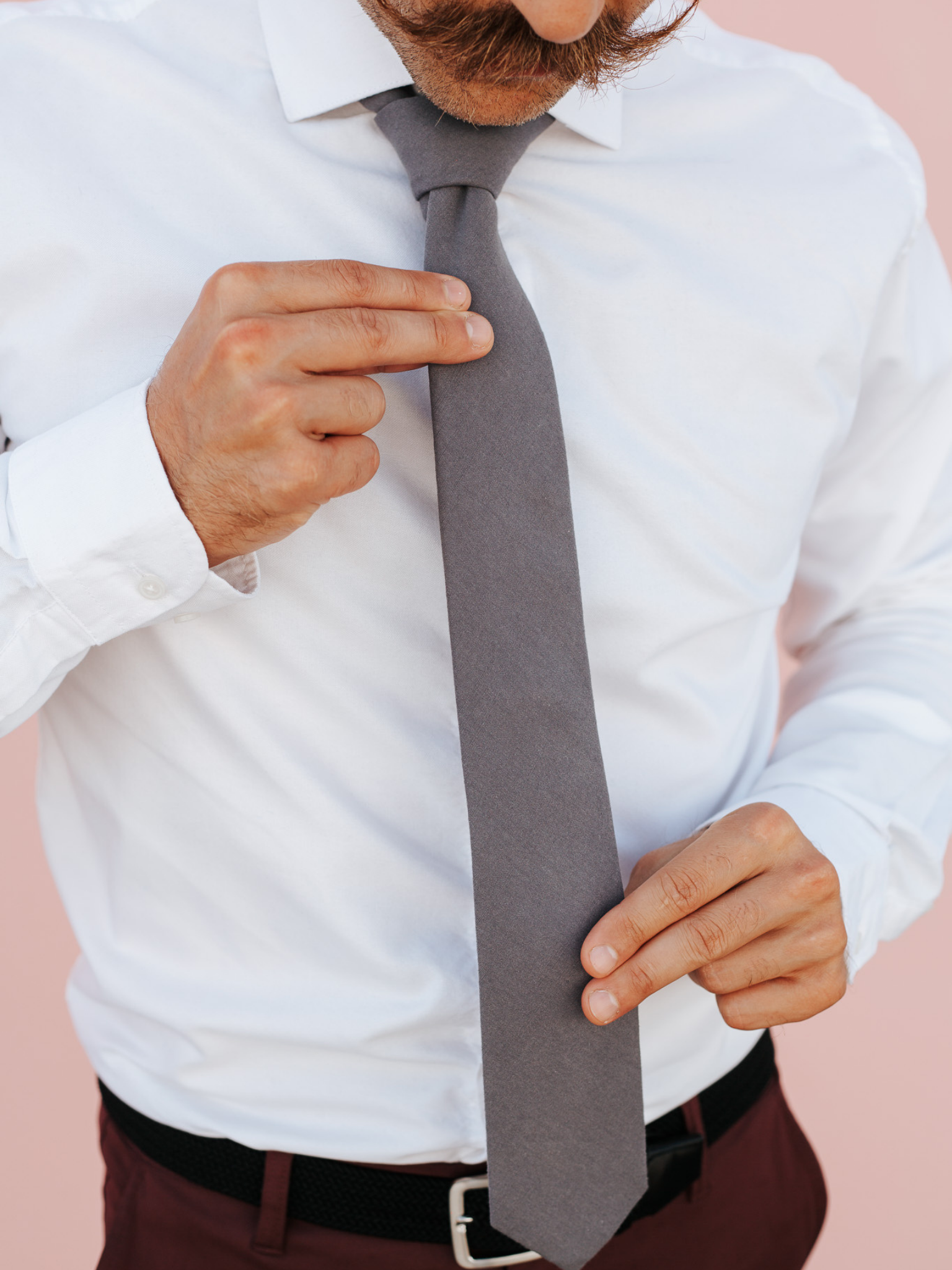 A close up of a man wearing a dark gray/grey solid-colored cotton skinny tie for weddings, grooms, and groomsmen.