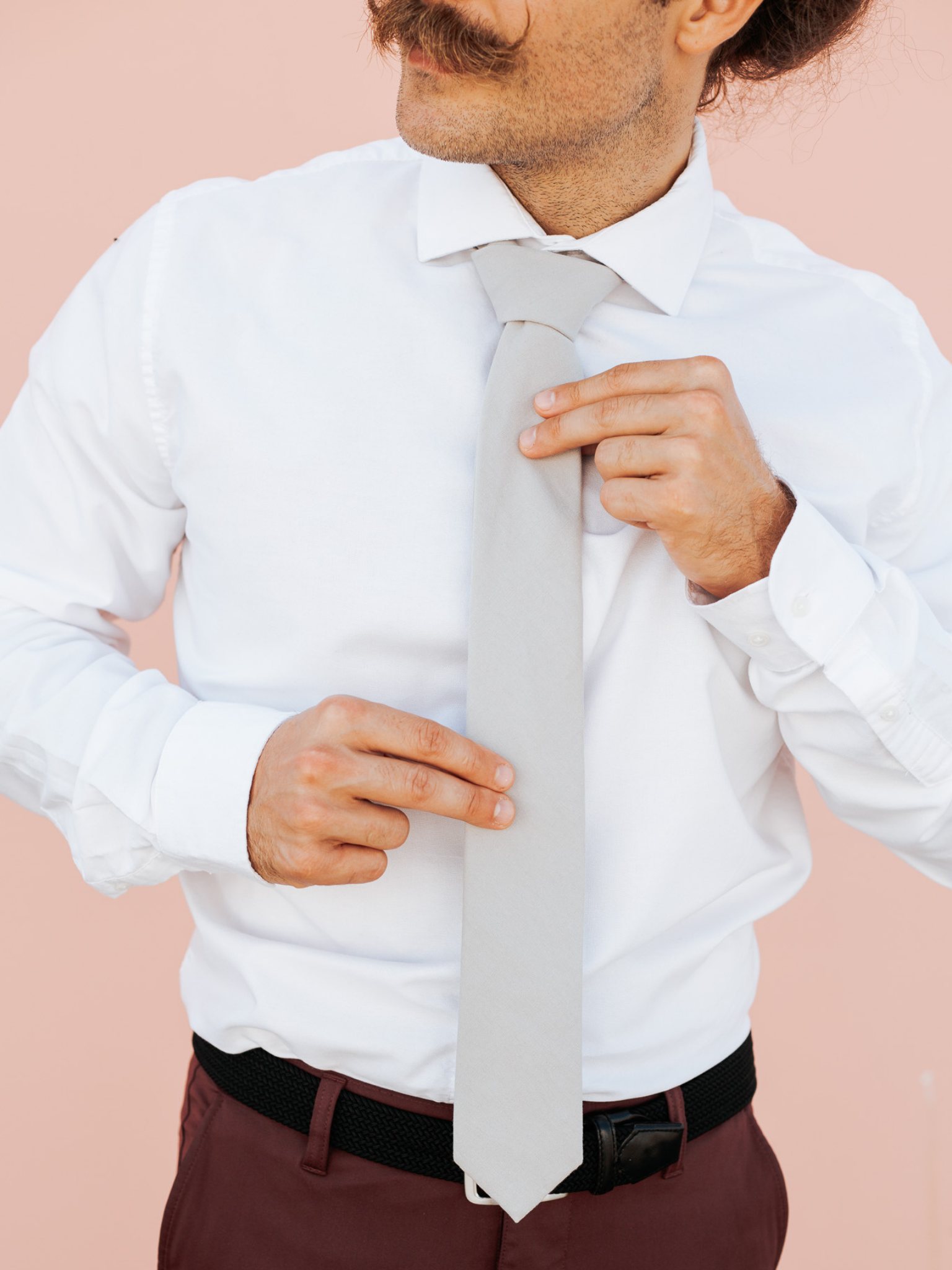 A close up of a man wearing a light sandy tan solid-colored cotton skinny tie for weddings, grooms, and groomsmen.