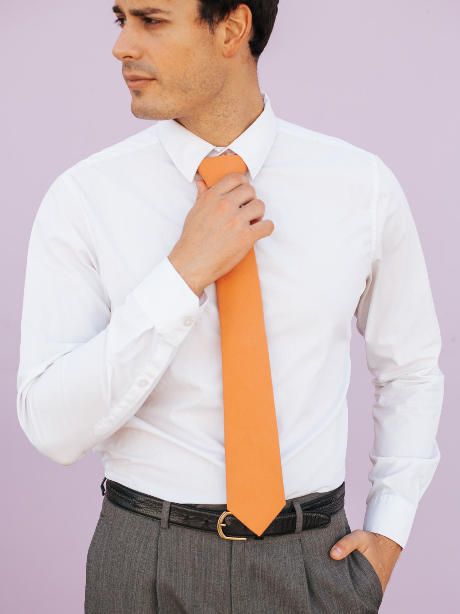 A close up of a man wearing a burnt orange salmon solid-colored cotton skinny tie for weddings, grooms, and groomsmen.