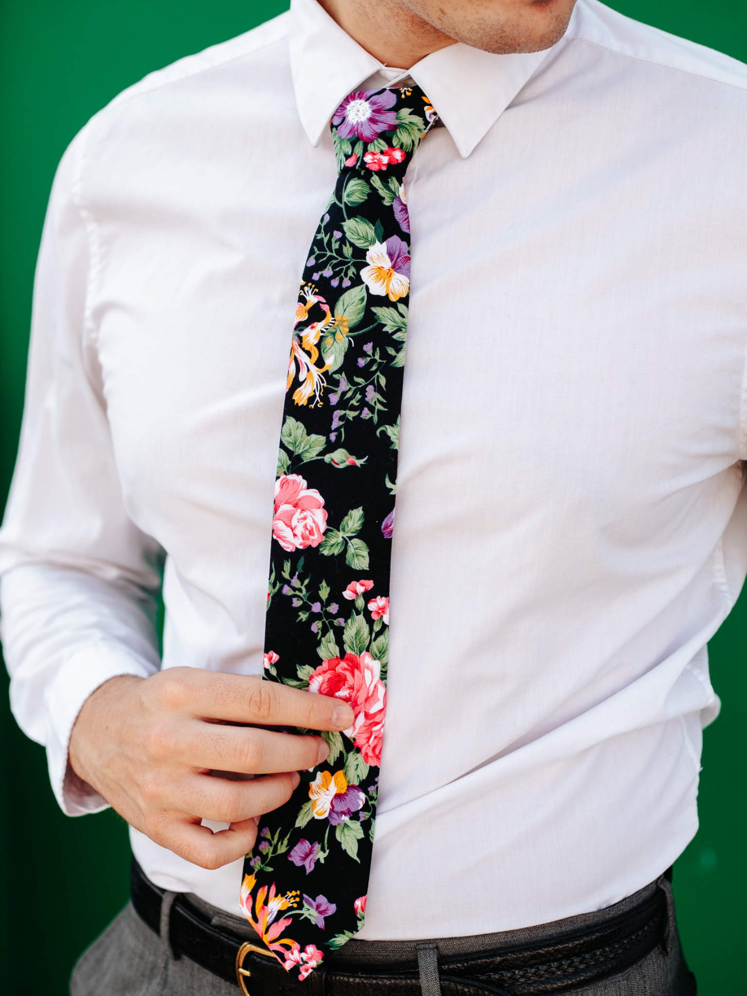 A close up of a man wearing a black and green flower cotton skinny tie for weddings, grooms, and groomsmen.