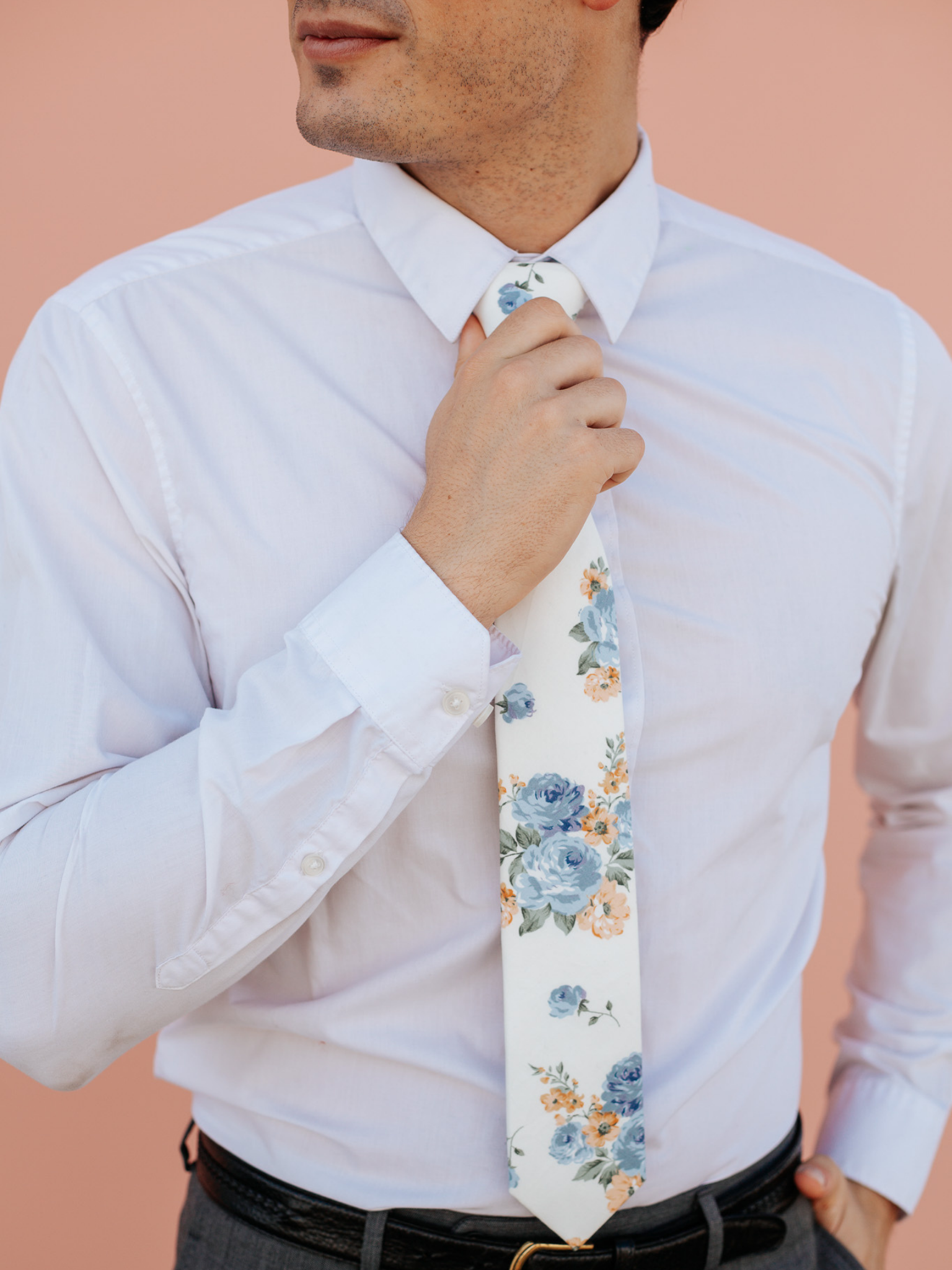 A close up of a man wearing a beige and blue flower cotton skinny tie for weddings, grooms, and groomsmen.