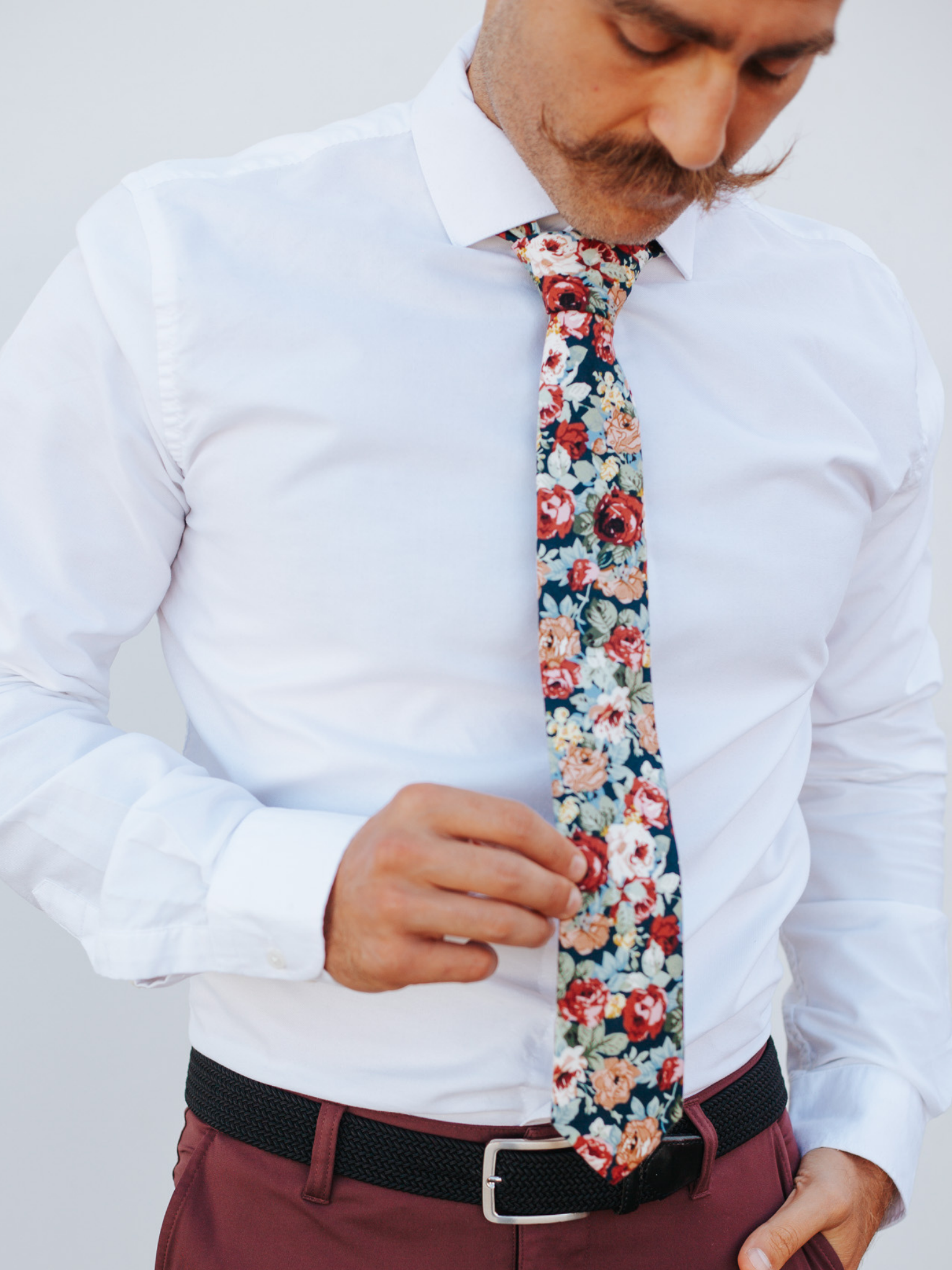 A close up of a man wearing a navy and red flower cotton skinny tie for weddings, grooms, and groomsmen.