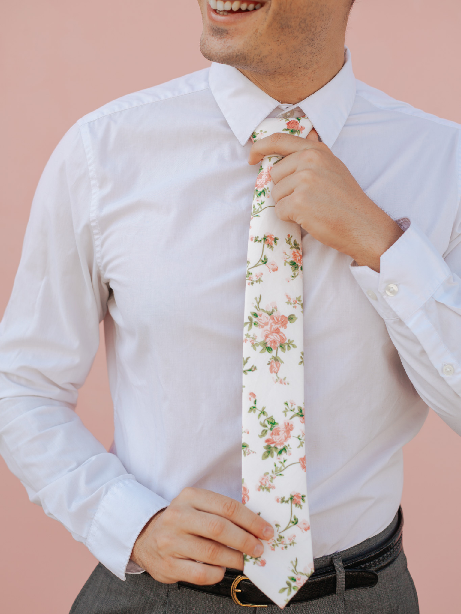 A close up of a man wearing a beige and pink flower cotton skinny tie for weddings, grooms, and groomsmen.