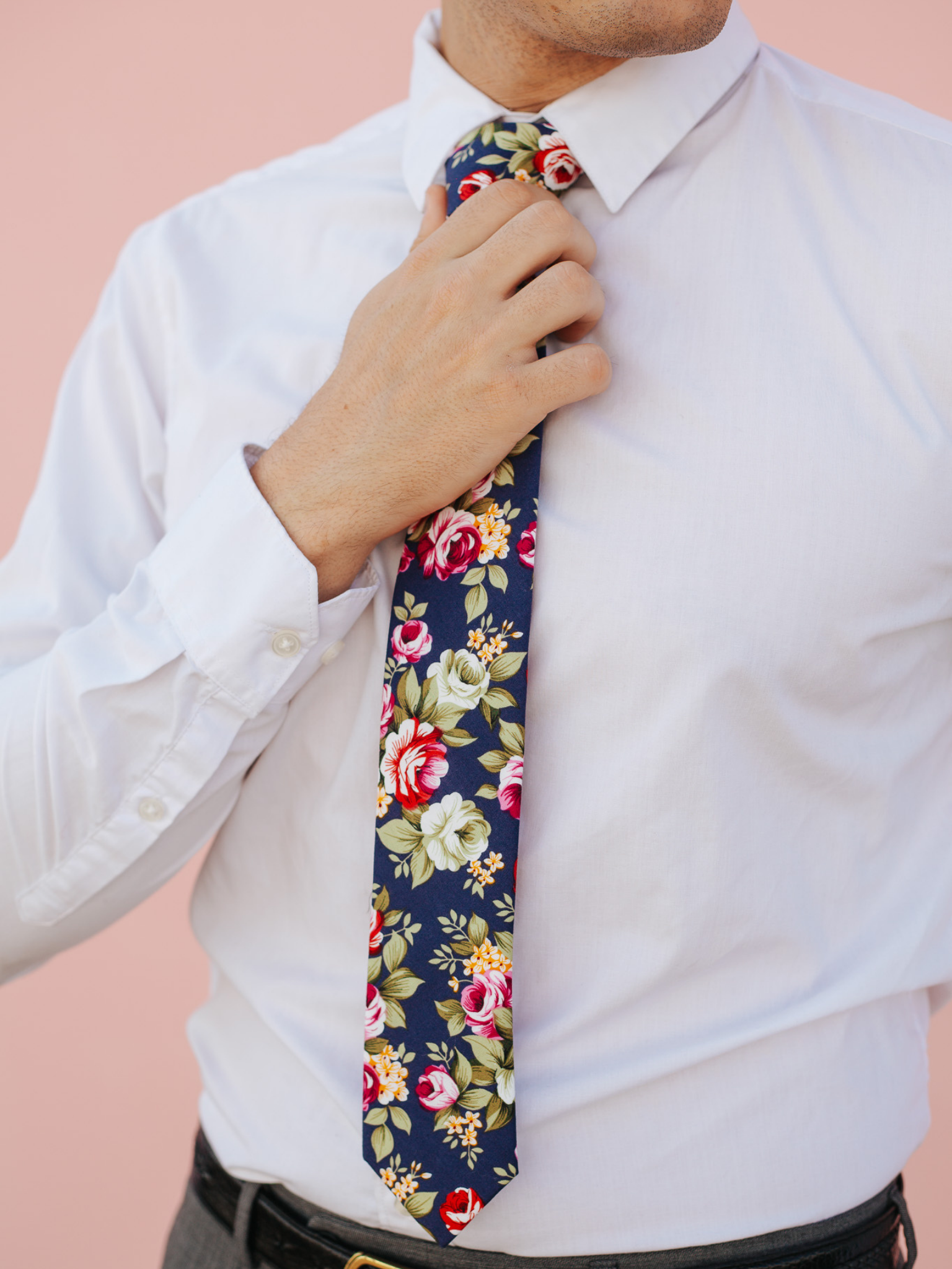 A close up of a man wearing a navy and pink flower cotton skinny tie for weddings, grooms, and groomsmen.