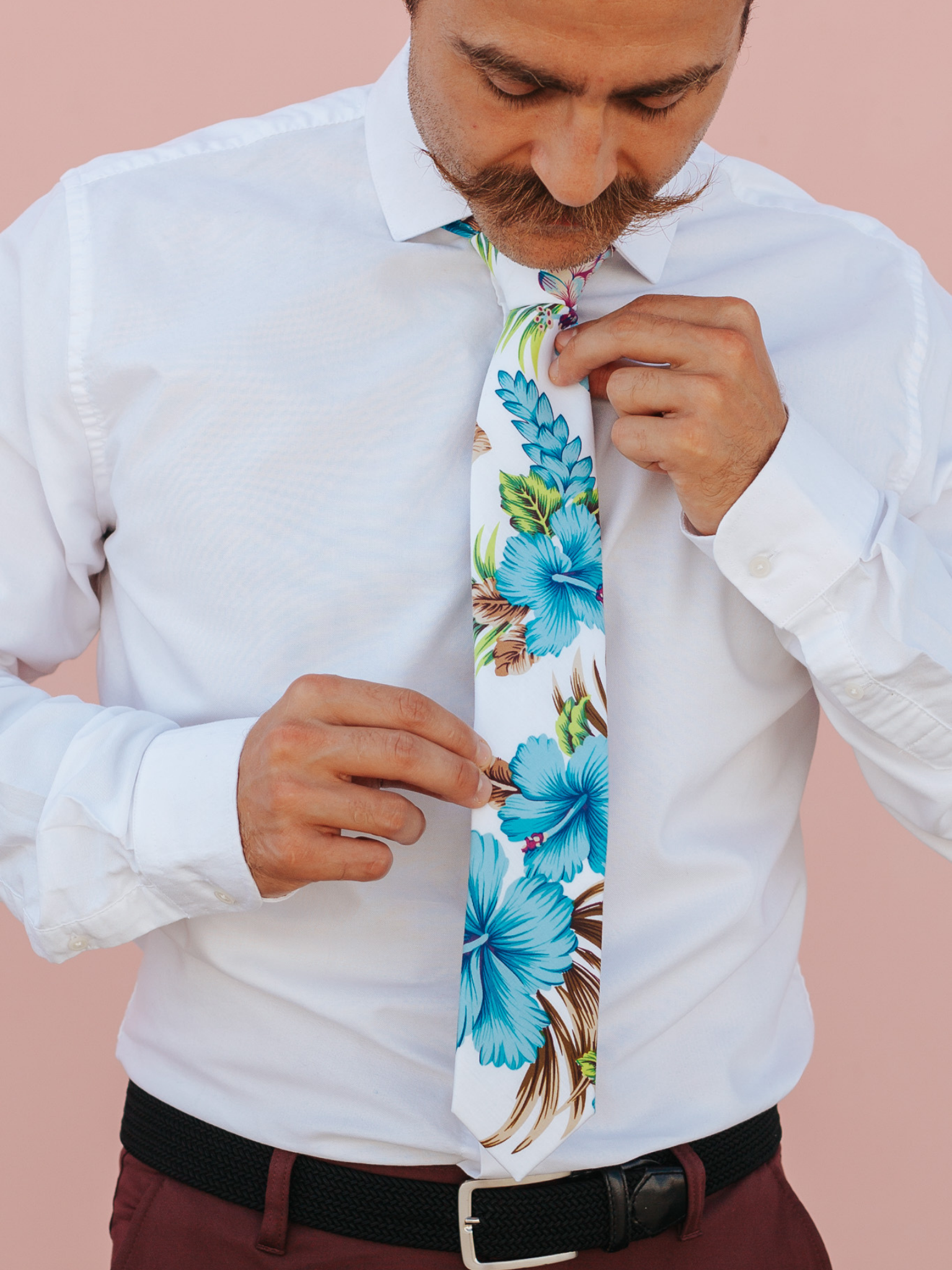 A close up of a man wearing a white and blue flower cotton skinny tie for weddings, grooms, and groomsmen.