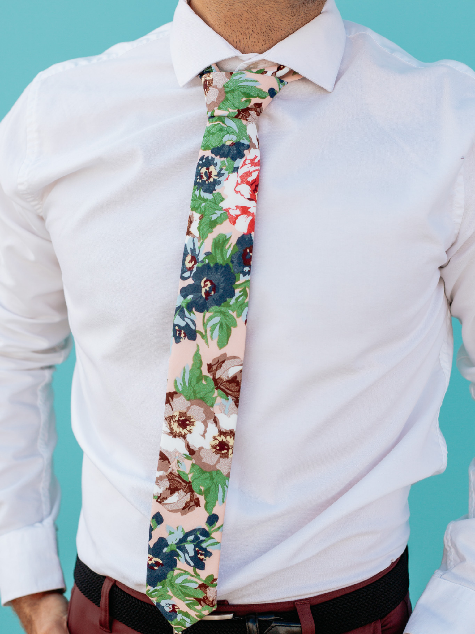 A close up of a man wearing a pink, green, and blue flower cotton skinny tie for weddings, grooms, and groomsmen.