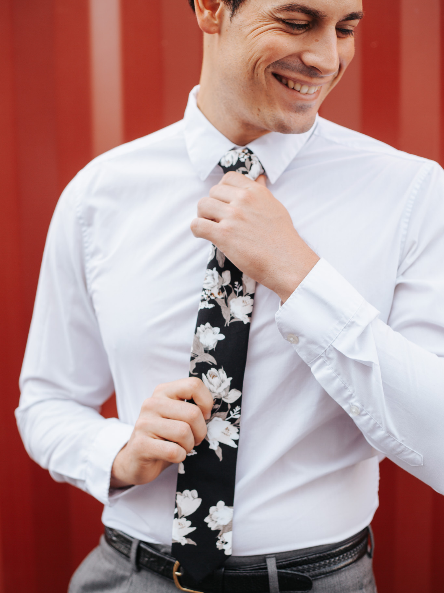 A close up of a man wearing a black and white flower cotton skinny tie for weddings, grooms, and groomsmen.